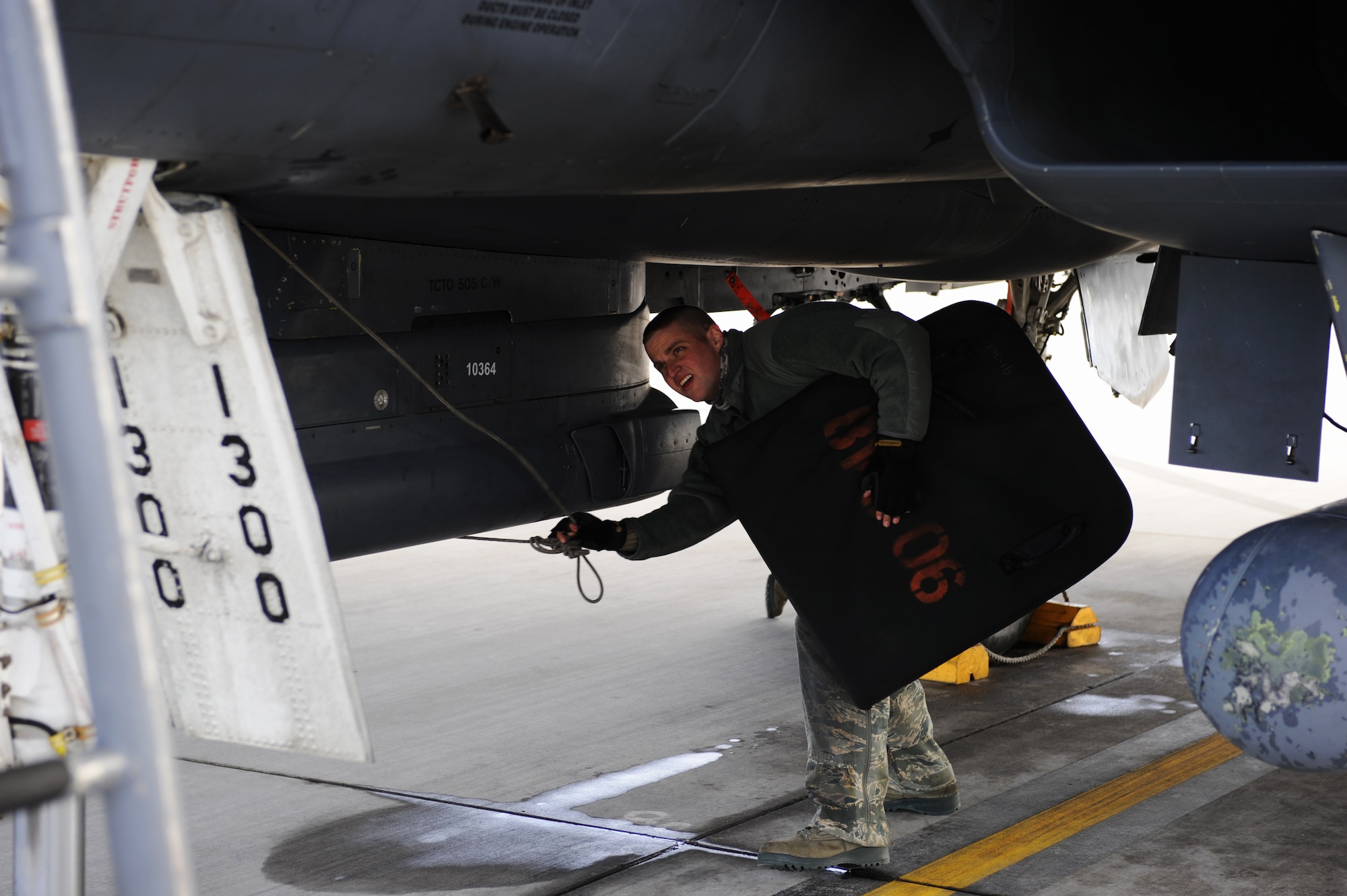 U.S. Air Force Airman First Class Justin Bacon, 366th Aircraft Maintenance Squadron F-15E Strike Eagle assistant dedicated crew chief for the Bold Tigers, holds an intake cover while working beneath an aircraft Jan. 30, 2013, at Mountain Home Air Force Base, Idaho. Flightline personnel had inspectors looking at programs and overall practices ensuring they are performing general maintenance in compliance with set standards throughout the week. (U.S. Air Force photo/Senior Airman Benjamin Sutton)  