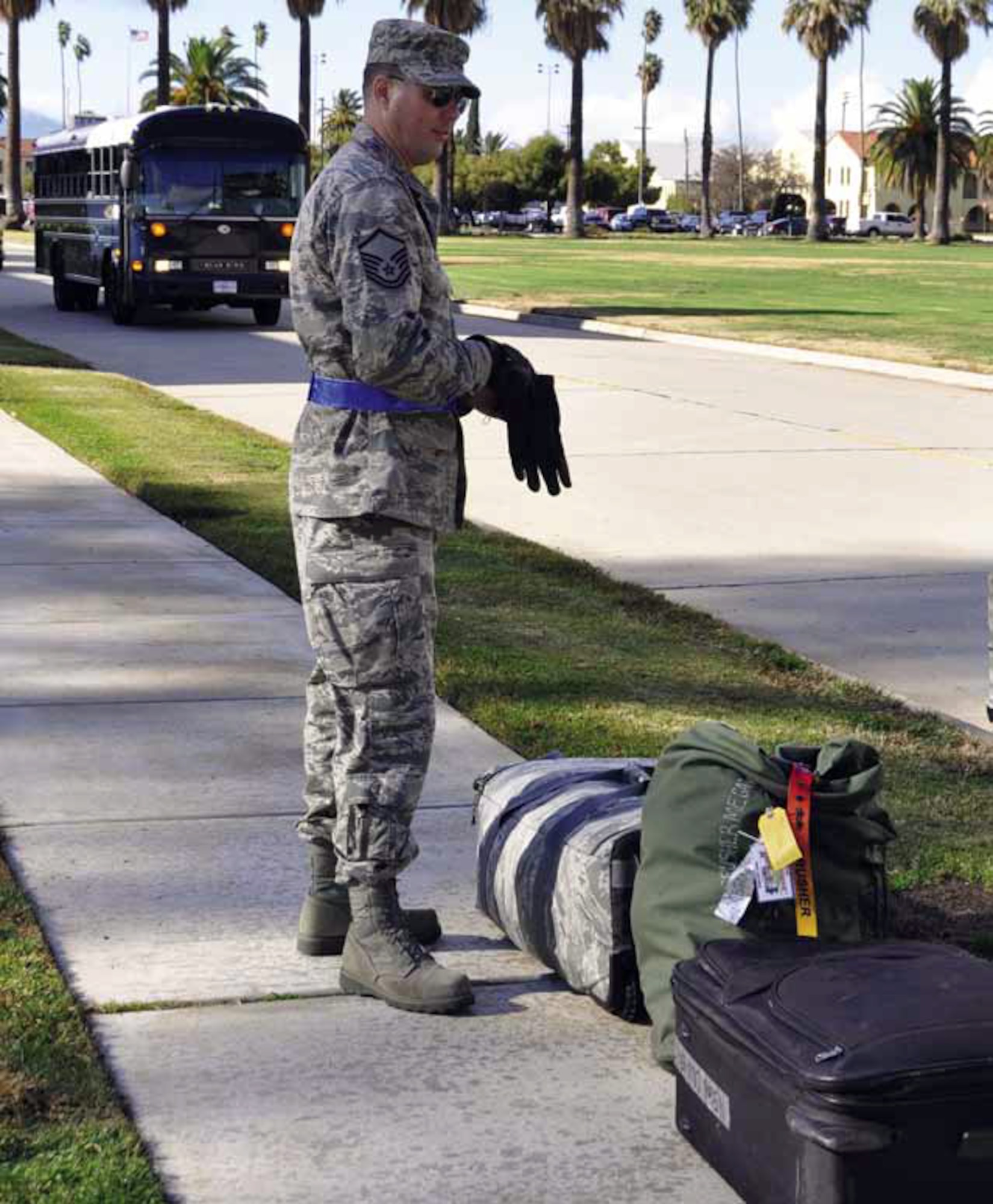 Master Sgt. John Hale, 452d AMW historian, prepares to load bags on a truck as he awaits bus transportation to the deployment processing area. Gloves are required to be worn when loading bags. (U.S. Air Force photo by Master Sgt. Linda Welz)