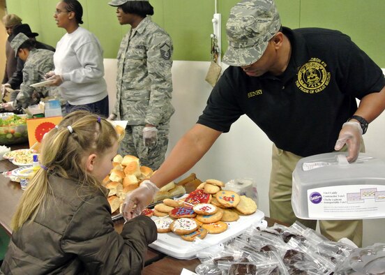Right, Staff Sgt. Henry Taylor, 48th Security Forces Squadron, hands a child a homemade cookie during the dinner that was served at the Family Links event Jan. 31, 2013, at Lakenheath Intermediate School on RAF Lakenheath, England. The event is specifically designed to help children and parents cope with the challenges of deployments, and was open to any military member or Department of Defense civilian who deploys and has children. More than 30 families attended the event. (U.S. Air Force photo by Tech. Sgt. Stacia Zachary/Released)