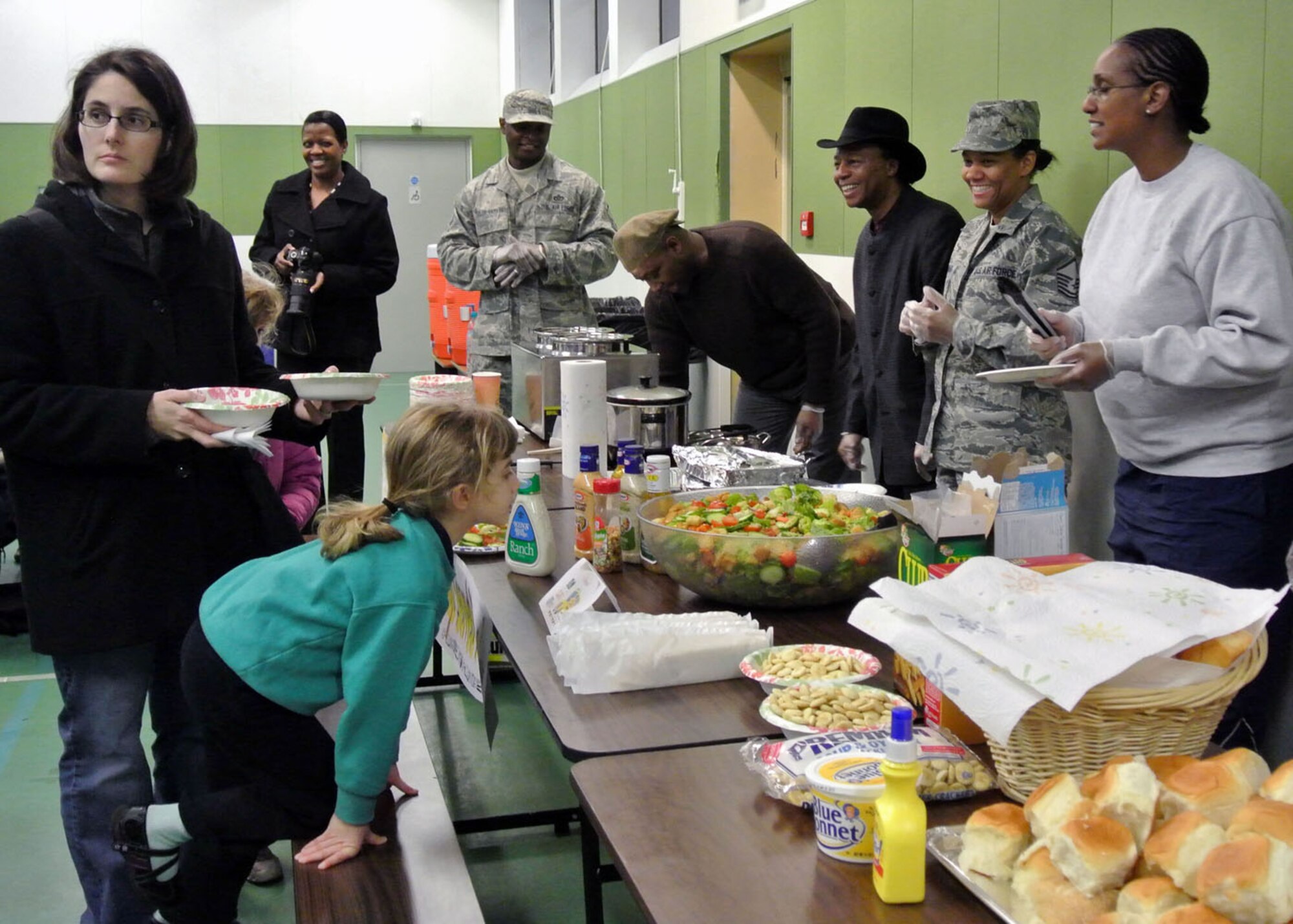 Christine Darling looks for a place to sit as daughter, Claire, 5, decides between gumbo or homemade chicken noodle soup during the dinner portion of the Family Links event Jan. 31, 2013, at Lakenheath Intermediate School on RAF Lakenheath, England. The event is specifically designed to help children and parents cope with the challenges of deployments, and was open to any military member or Department of Defense civilian who deploys and has children. More than 30 families attended the event. (U.S. Air Force photo by Tech. Sgt. Stacia Zachary/Released)