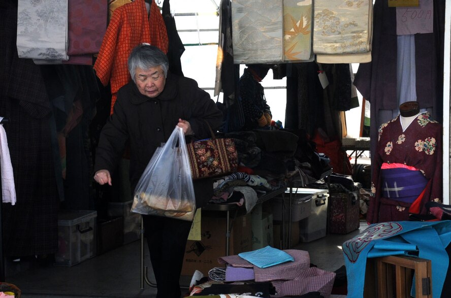 A Japanese customer walks out of a clothing stand at the Misawa 9th Day Market in Misawa City, Japan, Jan. 29, 2013. Fruit, vegetables and fish are not the only things sold at the farmers market. Off to the side or in the back of the market, kitchenware, various household items, clothes, shoes, used kimonos and other trinkets can be found. (U.S. Air Force photo by Airman 1st Class Kenna Jackson)