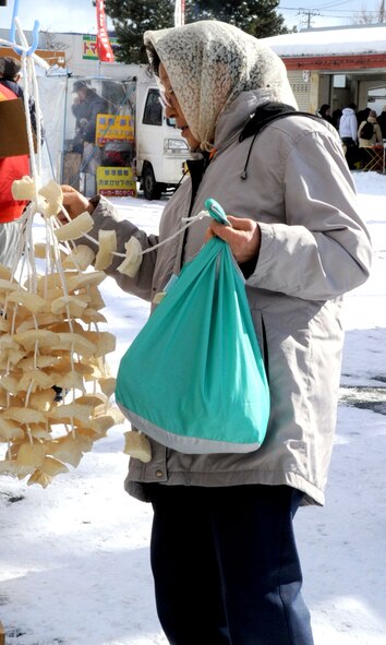 A Japanese customer examines a string of dried apples outside a stand at the Misawa 9th Day Market in Misawa City, Japan, Jan. 29, 2013. The 9th Day Market is a gathering of vendors who sell fresh produce directly from local farmers, rice field workers and fishermen. (U.S. Air Force photo by Airman 1st Class Kenna Jackson)