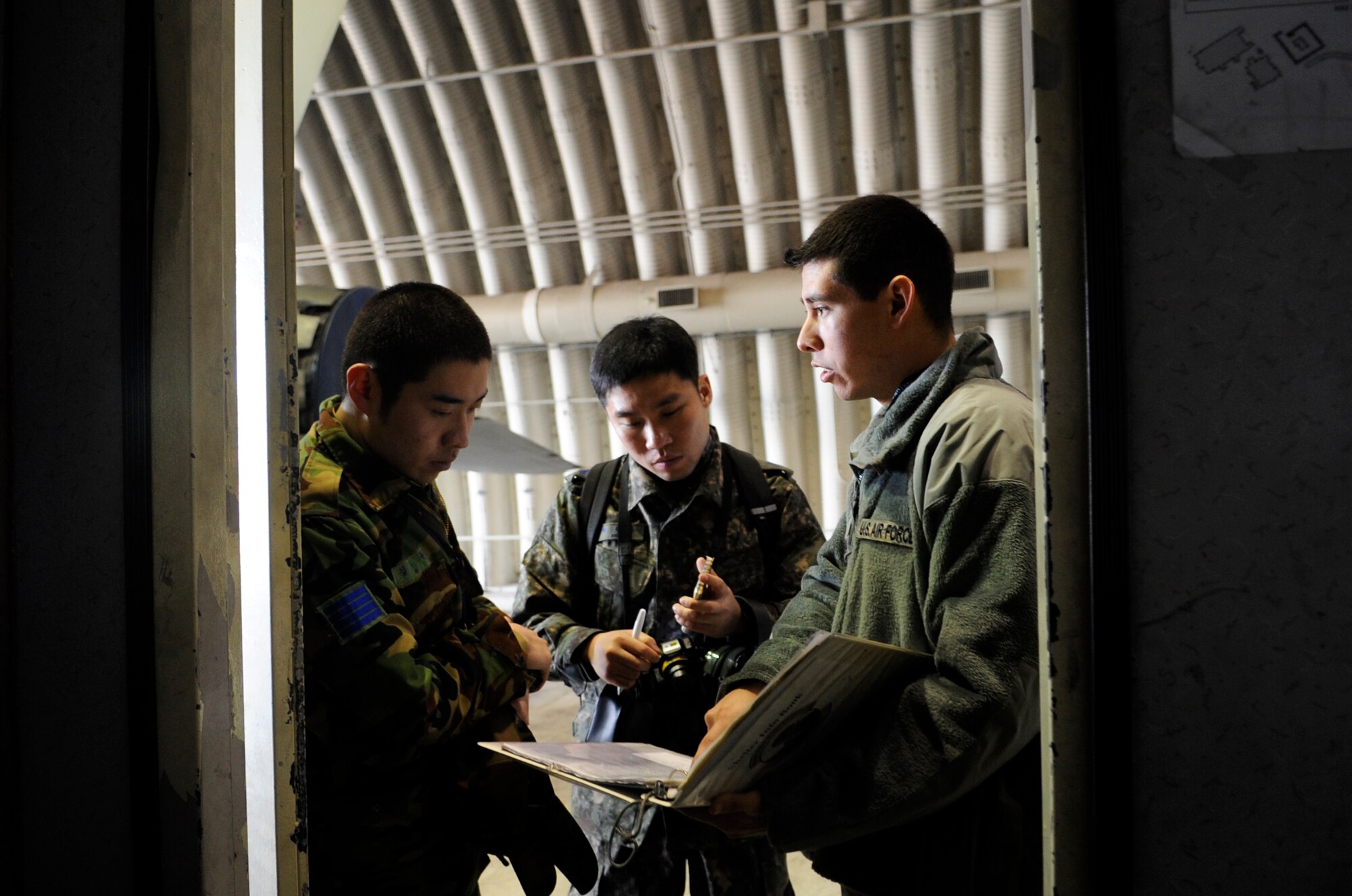 Senior Airman Javier Zepeda, right, 35th Aircraft Maintenance Unit crew chief, talks to Republic of Korea Air Force Master Sgt. Teun Teun Jung, center, and ROKAF Staff Sgt. Jeong Yong Kim, about differences in operating procedures Jan. 30, 2012, at Kunsan Air Base, Republic of Korea. This career exchange day gave the airmen a chance to learn how their counterparts work, an important step in strengthening the relationship between the U.S. and ROK air forces. (U.S. Air Force photo by Senior Airman Brigitte N. Brantley/Released)