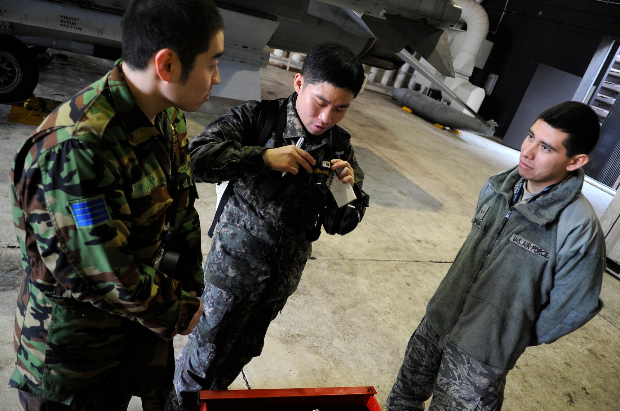 Republic of Korea Air Force Master Sgt. Teun Teun Jung, center, takes a picture of one of the 35th Aircraft Maintenance Unit’s toolboxes as ROKAF Staff Sgt. Jeong Yong Kim translates for Senior Airman Javier Zepeda, 35th AMU crew chief, Jan. 30, 2012, at Kunsan Air Base, Republic of Korea. Jung complimented the Air Force’s process of having a toolbox stationed in each hangar, as opposed to moving just a few around the flightline. (U.S. Air Force photo by Senior Airman Brigitte N. Brantley/Released)