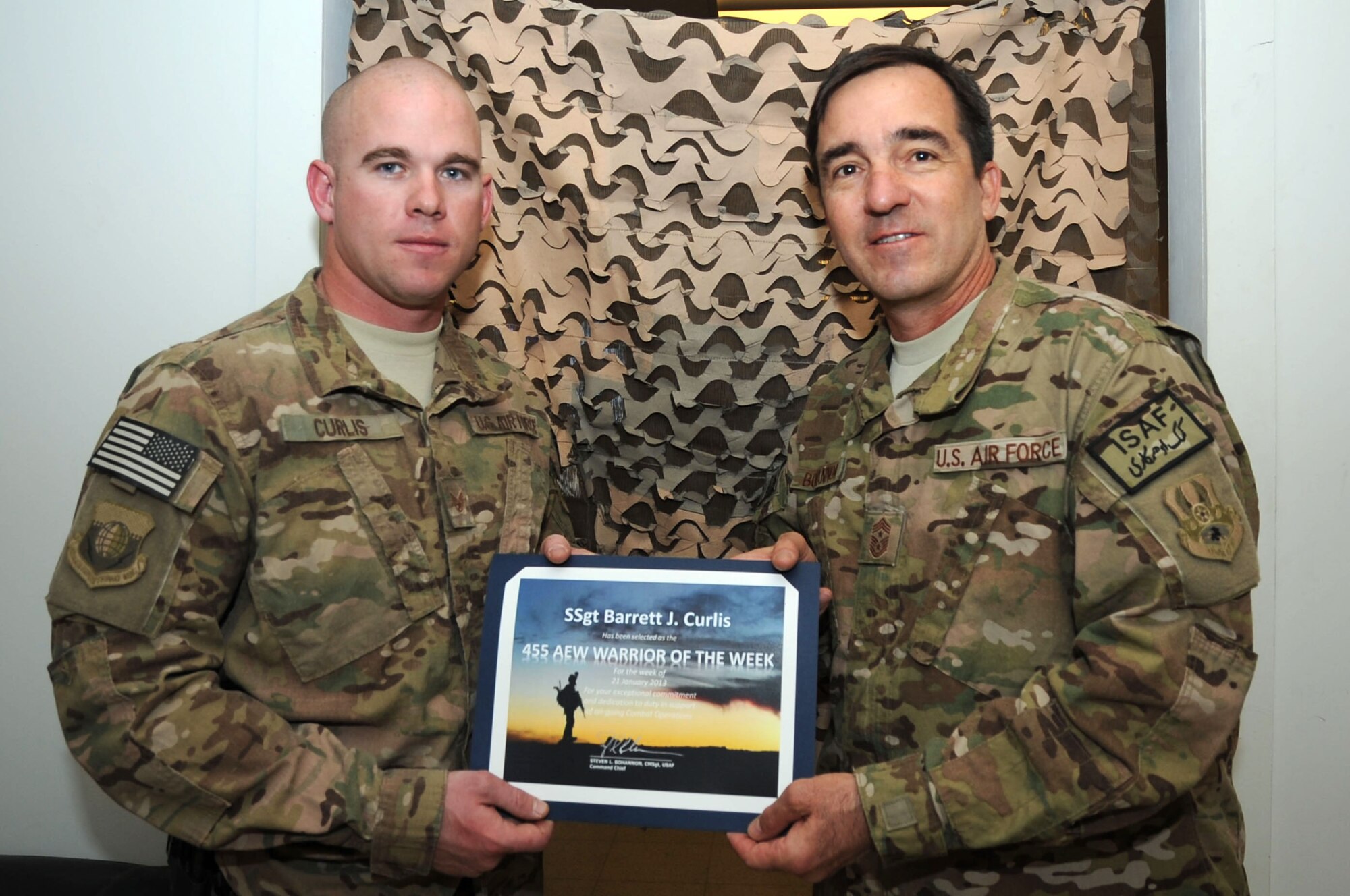 Chief Master Sgt. Steve Bohannon, Command Chief Master Sergeant of the 455th Air Expeditionary Wing, presents the "Warrior of the Week" award to Staff Sgt. Barrett Curlis, 455th Expeditionary Security Forces Group NCO in charge of physical security, on Bagram Airfield, Afghanistan, Jan. 23, 2013. Curlis leads personnel in hardening the base perimeter to deter attacks as well as conducts missions in the local area. (U.S. Air Force photo/Staff Sgt. David Dobrydney)