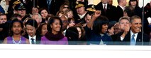 The Obama family cheers on a marching band from behind the reviewing stand glass during the 57th Presidential Inauguration parade in Washington, D.C., Jan. 21, 2013. As they enjoyed the entertainment of groups from all over the United States, National Guard members helped local and federal law enforcement keep people off of the parade route. (Air National Guard photo by Senior Airman Andrea F. Liechti)
