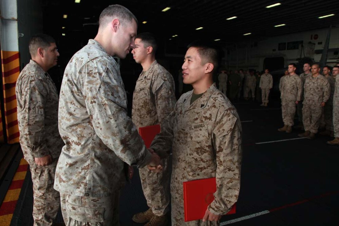 Newly promoted Cpl. Tony X. Pham, Headquarters and Service Company, Battalion Landing Team 3/5, 15th Marine Expeditionary Unit, shakes hands with Capt. Braxton H. Mashburn, his commanding officer, after receiving his new rank during a promotion ceremony held in the hangar bay of the USS Peleliu, Feb. 1. The 15th MEU is deployed as part of the Peleliu Amphibious Ready Group as a U.S. Central Command theater reserve force, providing support for maritime security operations and theater security cooperation efforts in the U.S. 5th Fleet area of responsibility. Pham, 21, is from West Minster, Calif. (U.S. Marine Corps photo by Cpl. John Robbart III)