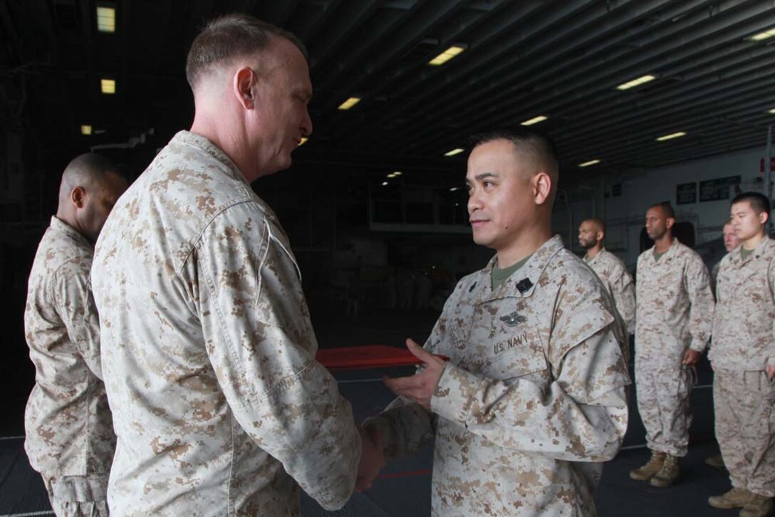 Hospital Corpsman 2nd Class Wendell Tabios, Command Element, 15th Marine Expeditionary Unit, receives a Certificate of Commendation from Col. Scott D. Campbell, his commanding officer, after being recognized as the unit's Junior Sailor of the Year during a ceremony held in the hangar bay of the USS Peleliu, Feb. 1. The 15th MEU is deployed as part of the Peleliu Amphibious Ready Group as a U.S. Central Command theater reserve force, providing support for maritime security operations and theater security cooperation efforts in the U.S. 5th Fleet area of responsibility. Tabios, 36, is from Cavite, Philippines. (U.S. Marine Corps photo by Cpl. John Robbart III)