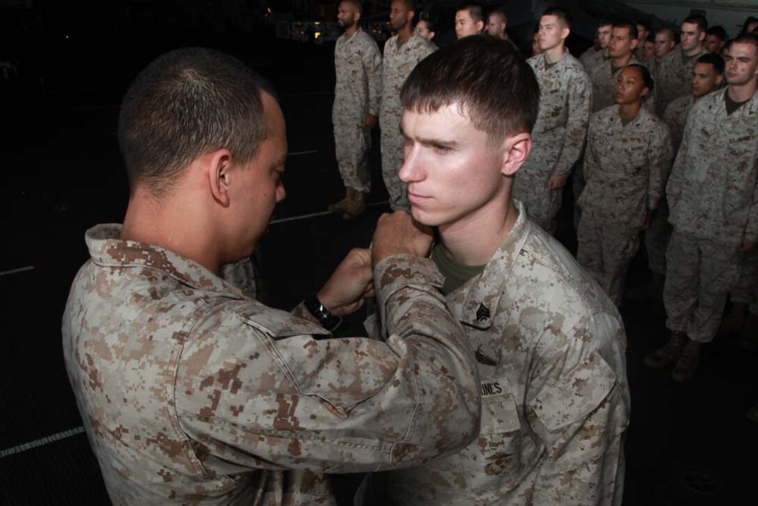 Newly promoted Sgt. Marvin T. Loverkamp, parachute rigger, Command Element, receives his new chevrons from Sergeant Nathan W. Contreras, parachute rigger, Force Reconnaissance Platoon, Maritime Raid Force, both with 15th Marine Expeditionary Unit, during a promotion ceremony held in the hangar bay of the USS Peleliu, Feb. 1. The 15th MEU is deployed as part of the Peleliu Amphibious Ready Group as a U.S. Central Command theater reserve force, providing support for maritime security operations and theater security cooperation efforts in the U.S. 5th Fleet area of responsibility. Loverkamp, 24, is from Brookport, Ill., and Contreras, 23, is from Los Lunas, N.M. (U.S. Marine Corps photo by Cpl. John Robbart III)