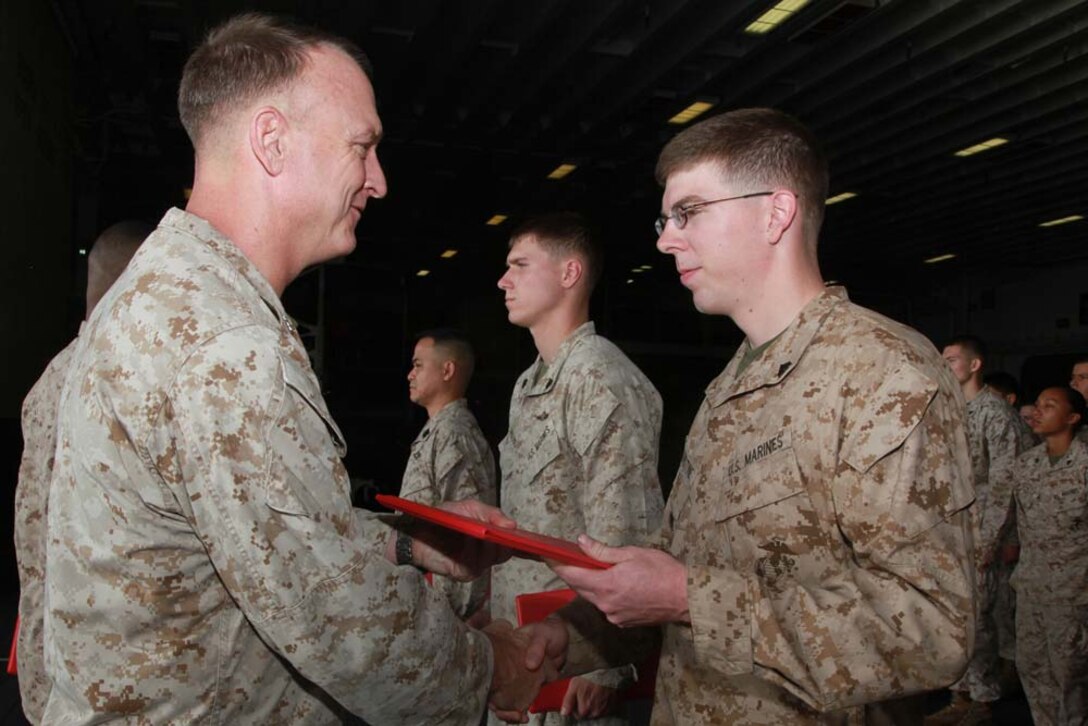 Newly promoted Cpl. Nehemiah V. Robenstine, assessment consequence management team member, Chemical Biological Radiological Nuclear Defense Detachment, 15th Marine Expeditionary Unit, receives his promotion warrant from Col. Scott D. Campbell, his commanding officer, after being promoted during a ceremony held in the hangar bay of the USS Peleliu, Feb. 1. The 15th MEU is deployed as part of the Peleliu Amphibious Ready Group as a U.S. Central Command theater reserve force, providing support for maritime security operations and theater security cooperation efforts in the U.S. 5th Fleet area of responsibility. Robenstine, 23, is from Glen Carbon, Ill. (U.S. Marine Corps photo by Cpl. John Robbart III)