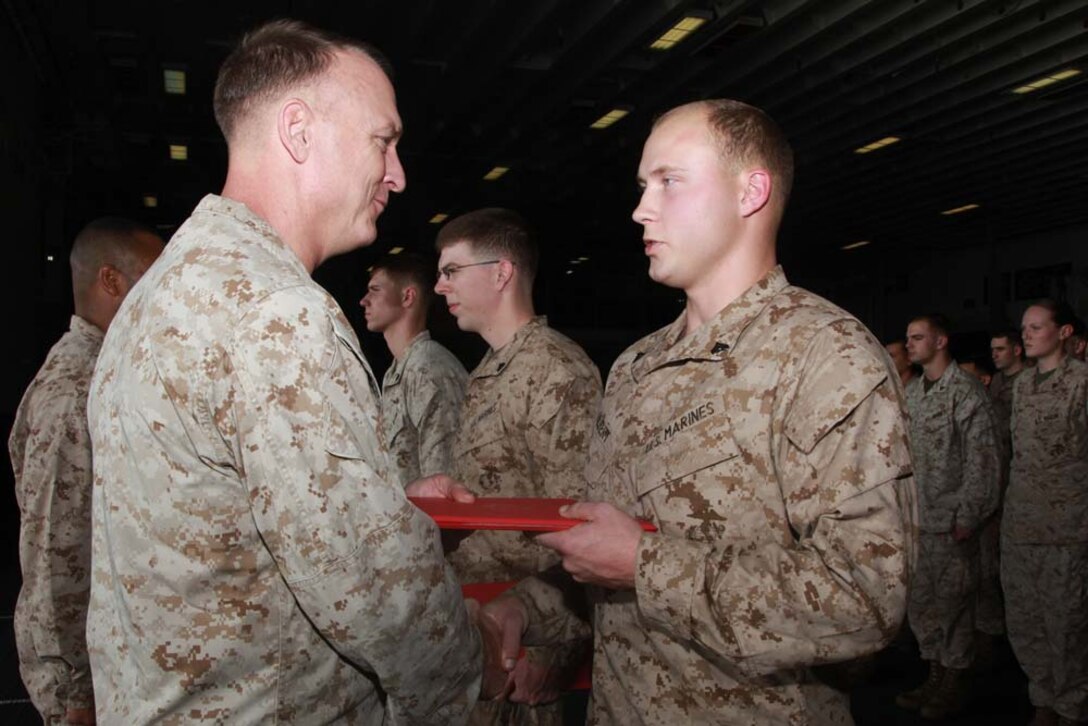 Newly promoted Cpl. Matthew E. Gilbert, intelligence analyst, Command Element, 15th Marine Expeditionary Unit, receives his promotion warrant from Col. Scott D. Campbell, his commanding officer, after being promoted during a ceremony held in the hangar bay of the USS Peleliu, Feb. 1. The 15th MEU is deployed as part of the Peleliu Amphibious Ready Group as a U.S. Central Command theater reserve force, providing support for maritime security operations and theater security cooperation efforts in the U.S. 5th Fleet area of responsibility. Gilbert, 21, is from Cincinnati. (U.S. Marine Corps photo by Cpl. John Robbart III)