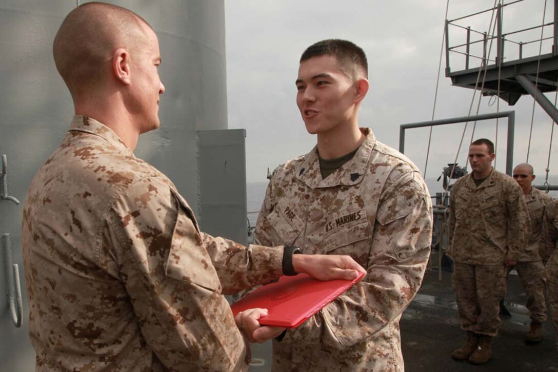 Newly promoted Sgt. Matthew Page, disbursing clerk, receives his promotion warrant from 1st Lt. Clayton Wiggins, disbursing officer, both with the 15th Marine Expeditionary Unit, on the USS Peleliu, Feb. 2. The 15th MEU is deployed as part of the Peleliu Amphibious Ready Group as a U.S. Central Command theater reserve force, providing support for maritime security operations and theater security cooperation efforts in the U.S. 5th Fleet area of responsibility. Page, 22, is from Hong Kong. (U.S. Marine Corps photo by Cpl. John Robbart III)