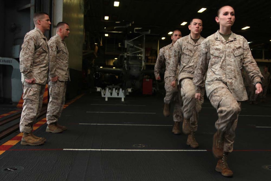 Marines with Marine Medium Helicopter Squadron 364 (Rein.), 15th Marine Expeditionary Unit, march to the front of the formation during a ceremony held in the hangar bay of the USS Peleliu, Feb. 2. The 15th MEU is deployed as part of the Peleliu Amphibious Ready Group as a U.S. Central Command theater reserve force, providing support for maritime security operations and theater security cooperation efforts in the U.S. 5th Fleet area of responsibility. (U.S. Marine Corps photo by Cpl. John Robbart III)