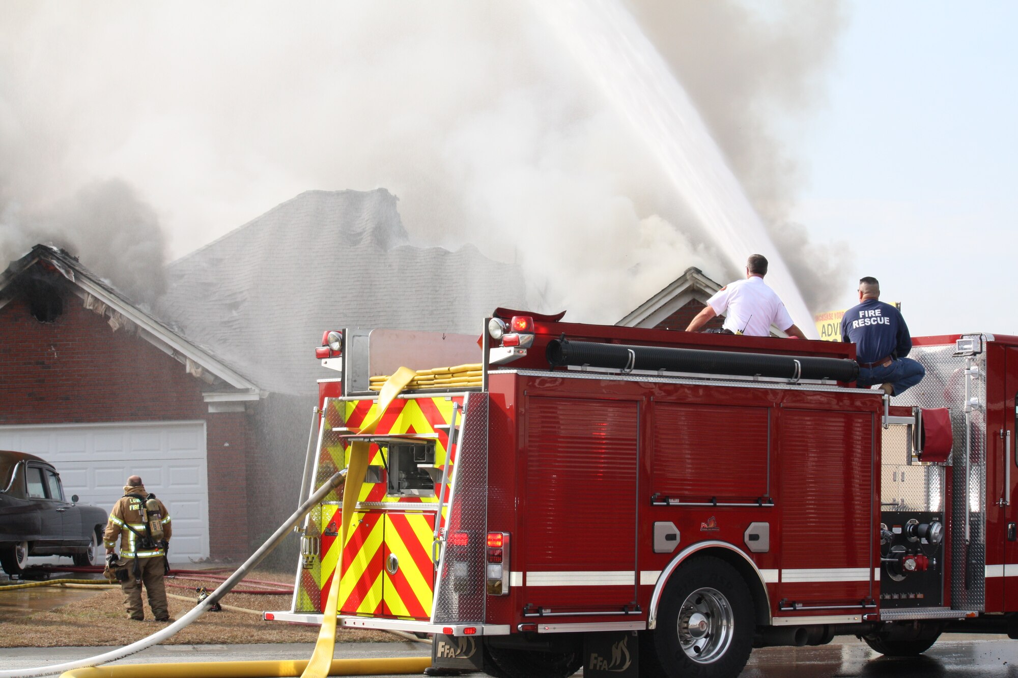 U.S. Air Force Master Sgt. Roderick Vega, 23d Wing deputy inspector general (right), and Capt. Lloyd Green, Lowndes County Fire Rescue, use the deck gun to extinguish a fire in Valdosta, Ga., Dec. 28, 2012. Vega has been a firefighter in the Air Force for 21 years. (Courtesy Photo)