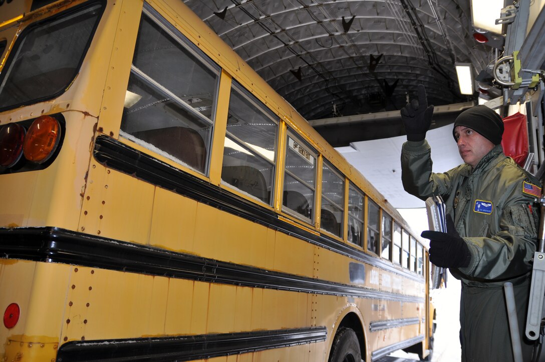 Air Force Reserve Tech. Sgt. Brian Farmintino, a loadmaster assigned to 437th Operations Group, Charleston Air Base, South Carolina, directs the driver to continue backing up the bus, here, February 2. The bus is going to Guatemala to help transport children in need. U.S. Air Force photo by Tech. Sgt. Valerie Smock