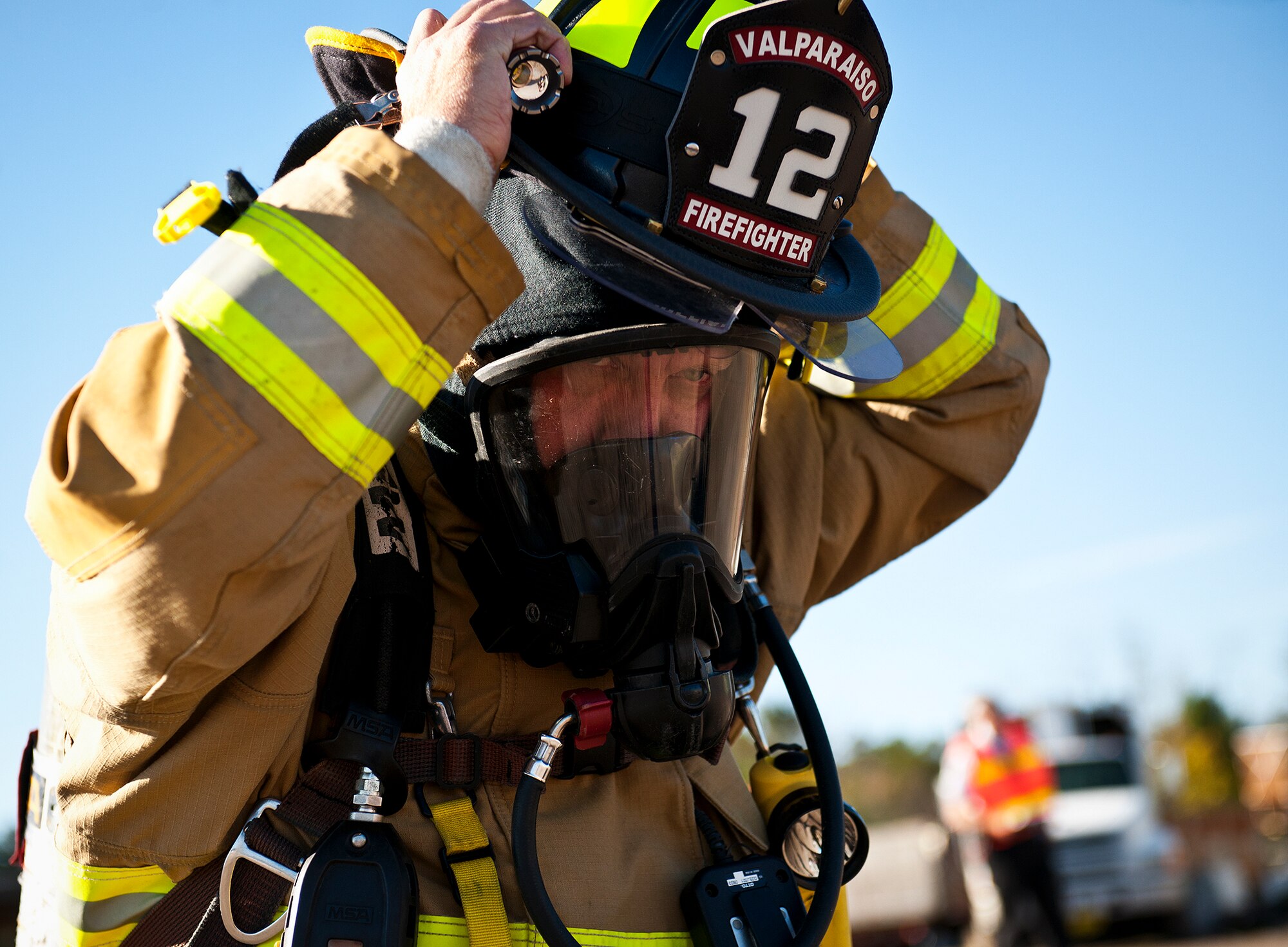 A member of the Valparaiso Fire Department adjusts his hat after putting on his gas mask during a joint major accident response exercise between Eglin Air Force Base and the city Jan. 31.  Emergency responders from the base and the city were called to a downed aircraft scenario featuring fire, wreckage and victims with multiple injuries.  The responders had to work as a team and coordinate movements at the simulated crash site, put out fires and attend to the wounded victims.  (U.S. Air Force photo/Samuel King Jr.)