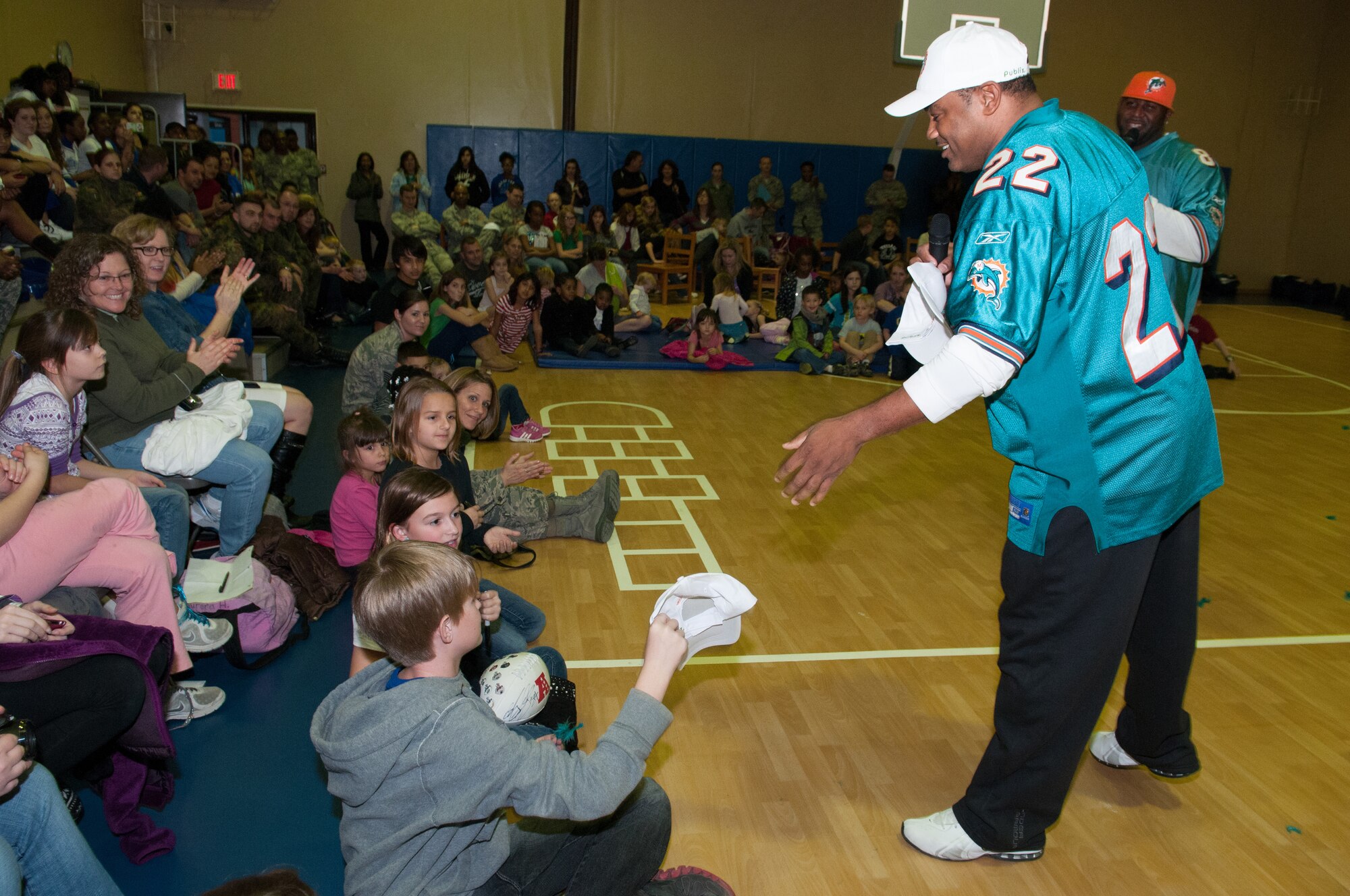 An Incirlik member receives a hat from Miami Dolphins alumni Troy Drayton and Shawn Wooden at the Youth Center, Jan. 30, 2013, as part of the Armed Forces Entertainment Super Bowl Tour to Incirlik Air Base, Turkey. The cheerleaders and football players made several appearances around the base including a radio show with the Incirlik American Forces Network, a cheer and football clinic with children and a performance at the Youth Center. (U.S. Air Force by Staff Sgt. Veuril McDavid/Released)
