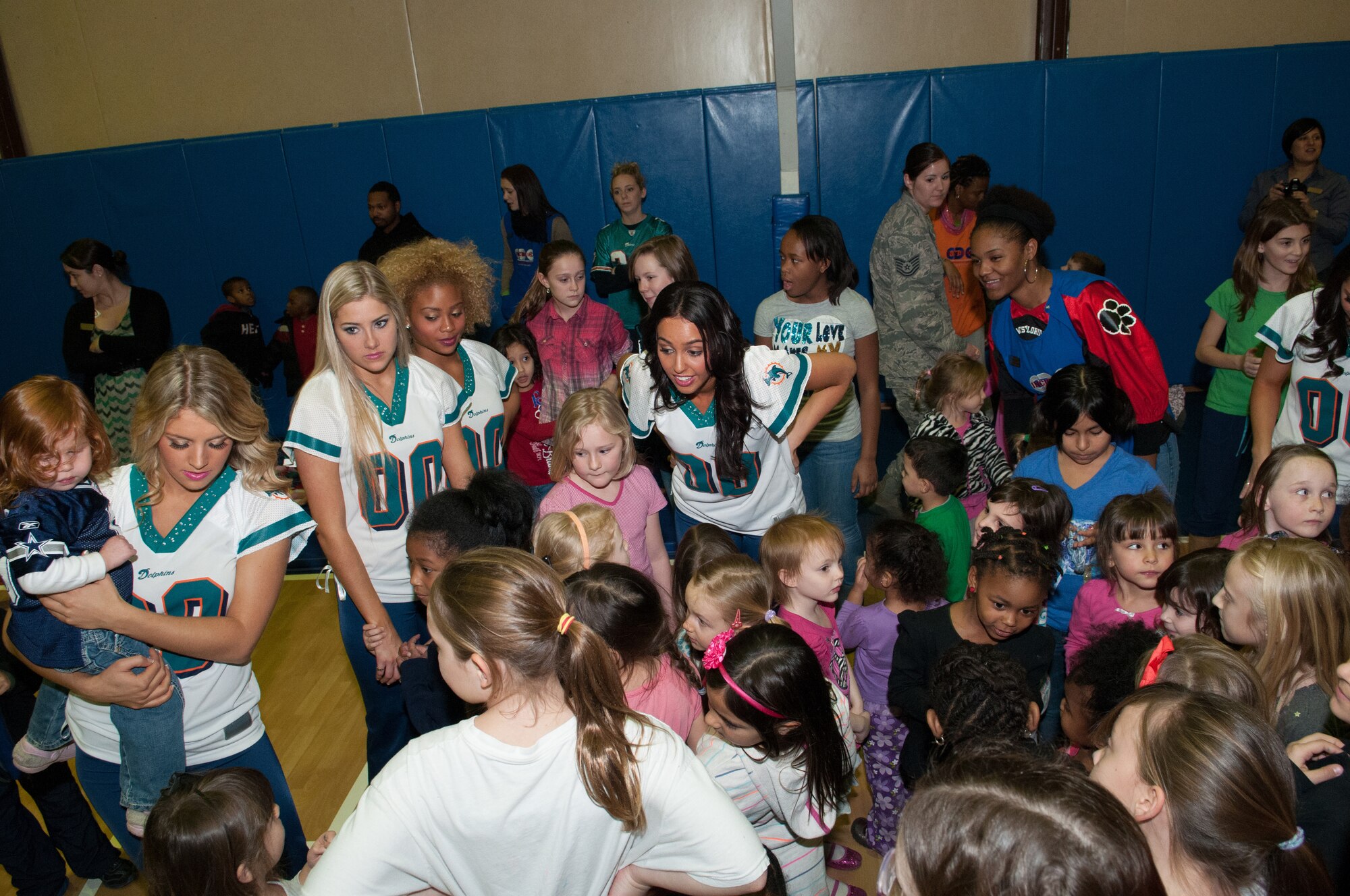 Incirlik children gather with Miami Dolphins Cheerleaders at the Youth Center, Jan. 30, 2013, at Incirlik Air Base, Turkey. The cheerleaders and football players made several appearances around the base as part of the Armed Forces Entertainment Super Bowl Tour including a radio show with the Incirlik American Forces Network, a cheer and football clinic with base children and a performance at the Youth Center. (U.S. Air Force by Staff Sgt. Veuril McDavid/Released)