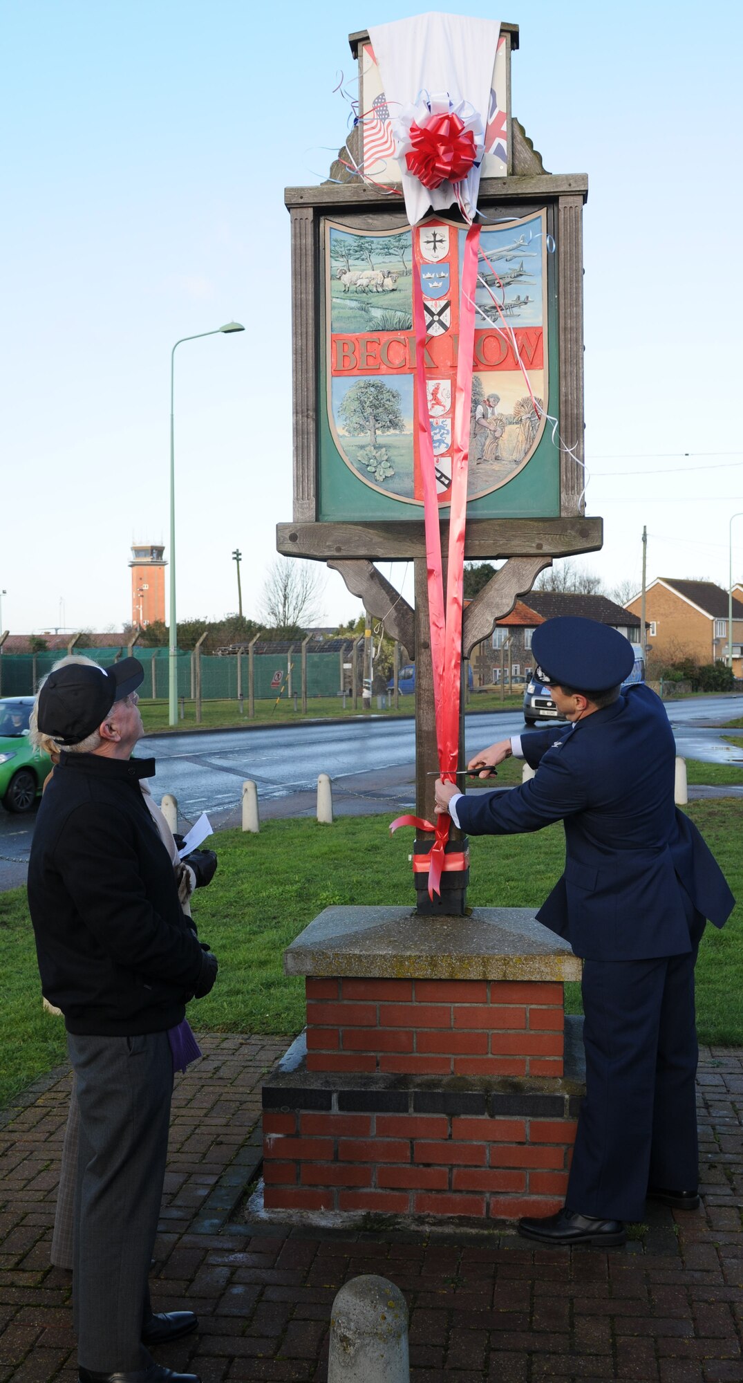Right, Col. Christopher Kulas, 100th Air Refueling Wing commander cuts the ribbon unveiling the new Beck Row sign Feb. 2, 2013, at Beck Row, England. The new sign symbolizes the unity between RAF Mildenhall and the local community.  (U.S. Air Force photo by Master Sgt. Latisha Cole/Released)