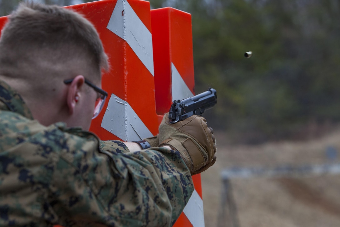 Lance Cpl. Joseph Lang, second platoon, Guard Company, Marine Barracks Washington, D.C., shoots an M9 handgun while taking cover behind a barrier during a training exercise at Marine Corps Base Quantico, Va., Jan. 30. The Marines conduct monthly, advanced CMP live-fire exercises in Quantico.  The training evolutions maintain their high levels of proficiency with the M4 carbine, M9 handgun and M1014 shotgun.  The Guard Marines fire on the move while engaging multiple targets, and utilize stress drills to sharpen their tactics.