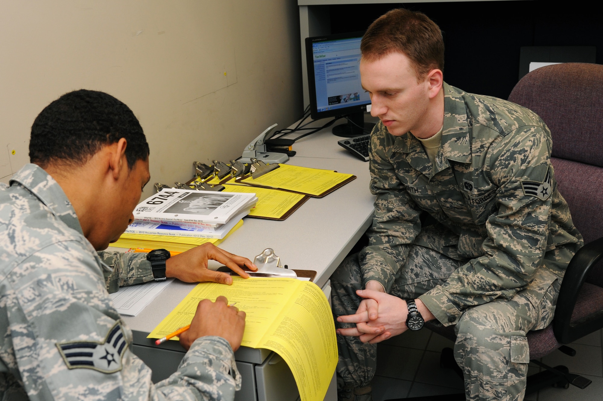 U.S. Air Force Senior Airman Holden Smith, 633rd Air Base Wing Judge Advocate paralegal, assists Senior Airman Terrence Eaton, logistics readiness squadron vehicle maintenance journeymen, in filling out a form at the Langley Air Force Base tax center, Va., Feb. 5, 2013. When filing taxes the documents needed are a social security card, photo ID, a blank check for direct deposit, and a W-2 form. (U.S. Air Force photo by Airman First Class Victoria Taylor/ Released)