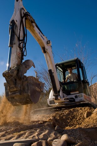 Senior Airman Andy Higginbotham, 99th Civil Engineer Squadron pavement equipment operator, uses a back hoe during the Ellsworth and Beale Road round about project Feb. 4, 2013 at Nellis Air Force Base, Nev. The new roundabout will reduce traffic and improve security measures on the base. (U.S. Air Force photo by Staff Sgt. William P. Coleman)  