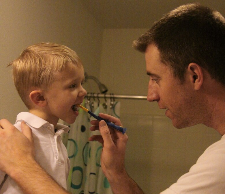 Capt. Brandon Bennett, 21st Dental Squadron, brushes his son's teeth. February is National Children’s Dental Health Month. The American Dental Association recommends that children younger than seven years receive help from an adult. (U.S. Air Force photo)