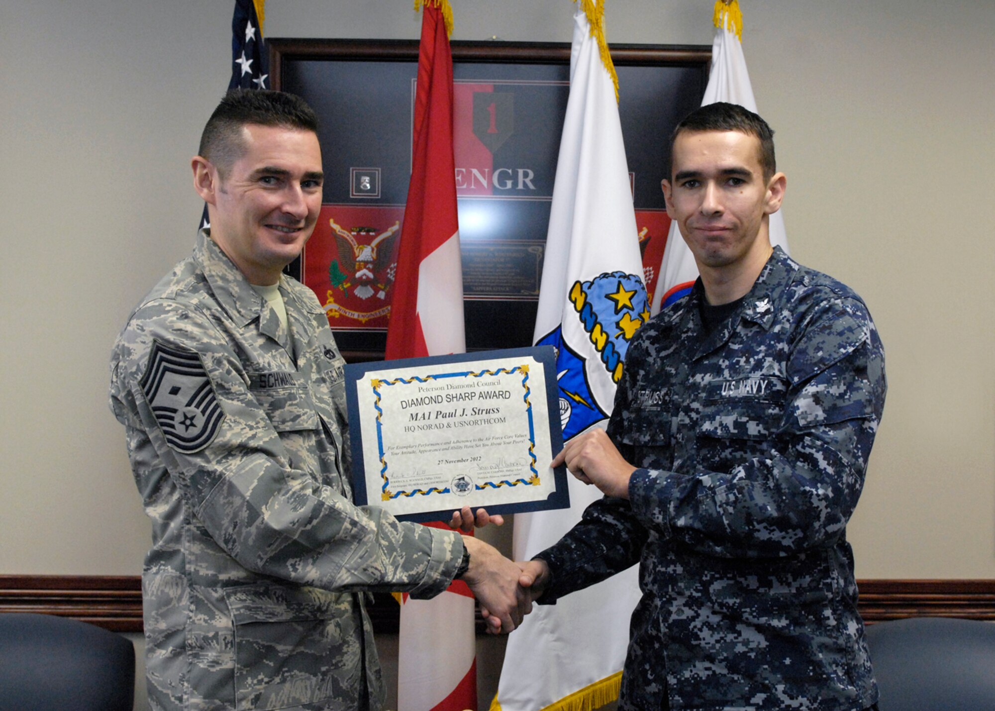PETERSON AIR FORCE BASE, Colo. – Chief Master Sgt. Roderick Schwald, Headquarters NORAD and U.S. Northern Command first sergeant, presents the Team Peterson First Sergeants Council Diamond Sharp Airman award to Petty Officer 1st Class Paul Struss. The award is based on outstanding demonstration of Air Force Core Values either off duty or in the performance of official duties. Struss is a master of arms first class at North American Aerospace Defense Command. Any first sergeant or senior NCO serving as a first sergeant who observes outstanding performance may nominate someone for the award to the first sergeants council. (U.S. Air Force photo) 