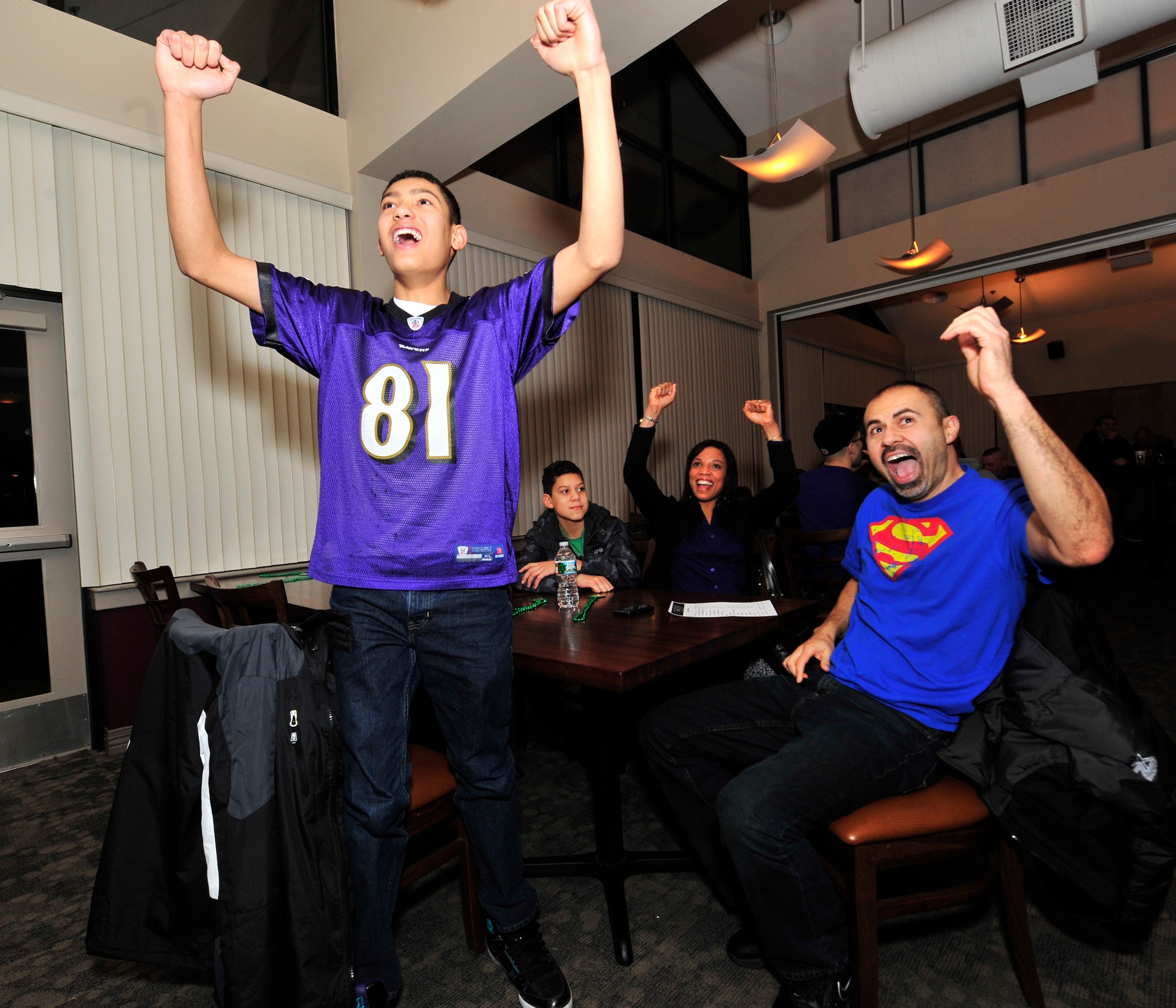 Christian Alfaro stands up and cheers following a Baltimore Ravens touchdown while his father Frank, mother Pam and brother Nicholas also cheer during the Super Bowl Feb. 3, 2013 at Mulligans Sports Bar and Grill on Dover Air Force Base, Del. The Ravens defeated the San Francisco 49ers 34-31. (U.S. Air Force photo by Tech. Sgt. Chuck Walker)