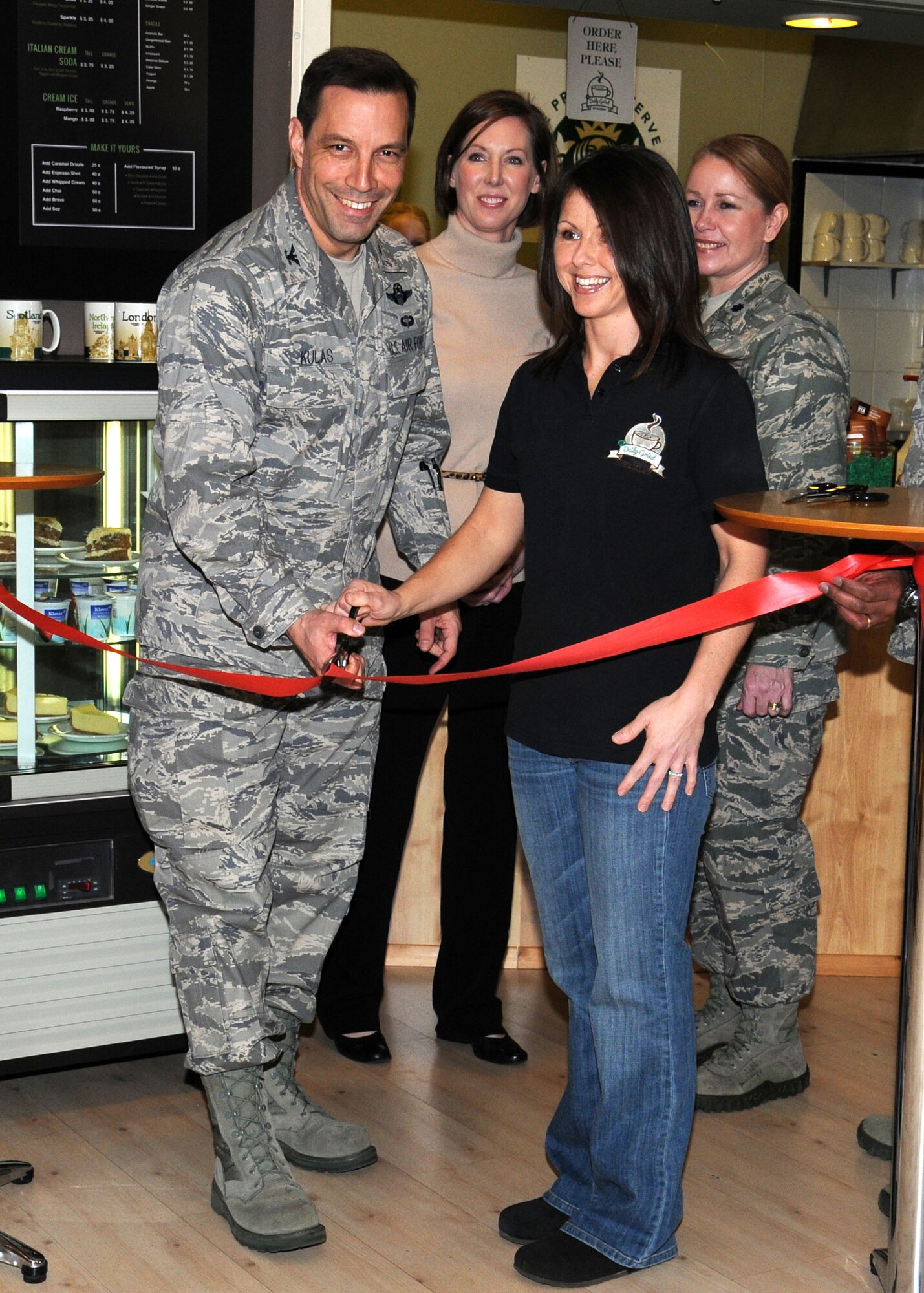 Col. Christopher Kulas, 100th Air Refueling Wing commander, and Dawn Updegrave, 100th Force Support Squadron Daily Grind supervisor, cut the ribbon to re-open the Daily Grind coffee shop in the Bob Hope Community Center Feb. 4, 2013, at RAF Mildenhall, England. The Daily Grind was re-opened following a two-week closure for renovation. (U.S. Air Force photo by Gina Randall/Released)