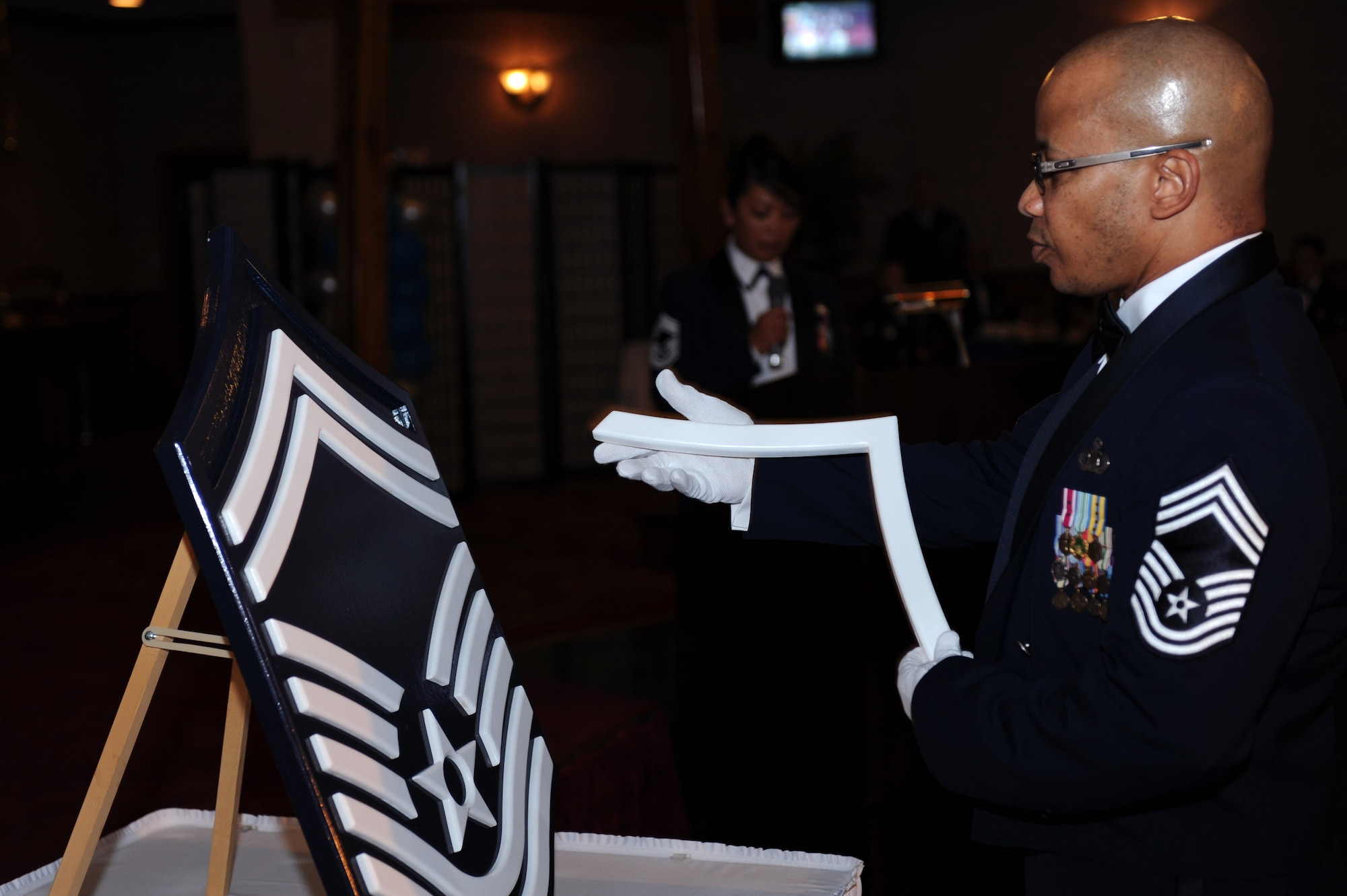 U.S. Air Force Chief Master Sgt. William Brown, 18th Operations Support Squadron superintendent, places the final chevron on a chief master sergeant insignia during the chief recognition ceremony at the Rocker NCO club on Kadena Air Base, Japan, Feb. 1, 2013. Enlisted service members also lit candles representing their enlisted rank. (U.S. Air Force photo/Airman 1st Class Hailey R. Davis)