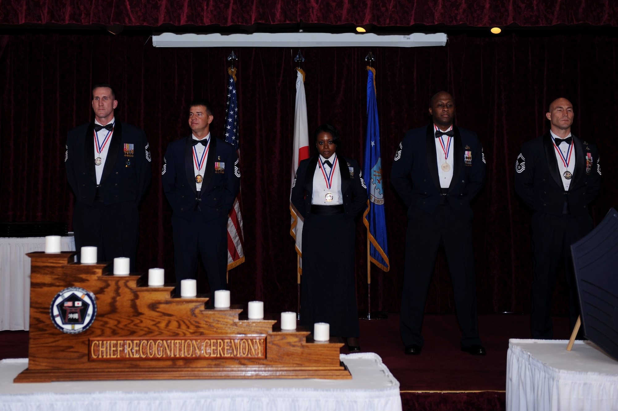 U.S. Air Force Senior Master Sgts. James Dwyer, Benjamin Winslow, Jennifer Bell, Ronald Harper and Jeffrey Guilmain, chief master sergeant promotees, stand at parade rest during the chief recognition ceremony at the Rocker NCO club on Kadena Air Base, Japan, Feb. 1, 2013. Enlisted service members placed corresponding chevrons on a chief master sergeant rank insignia and lit candles representing their enlisted rank. (U.S. Air Force photo/Airman 1st Class Hailey R. Davis)
