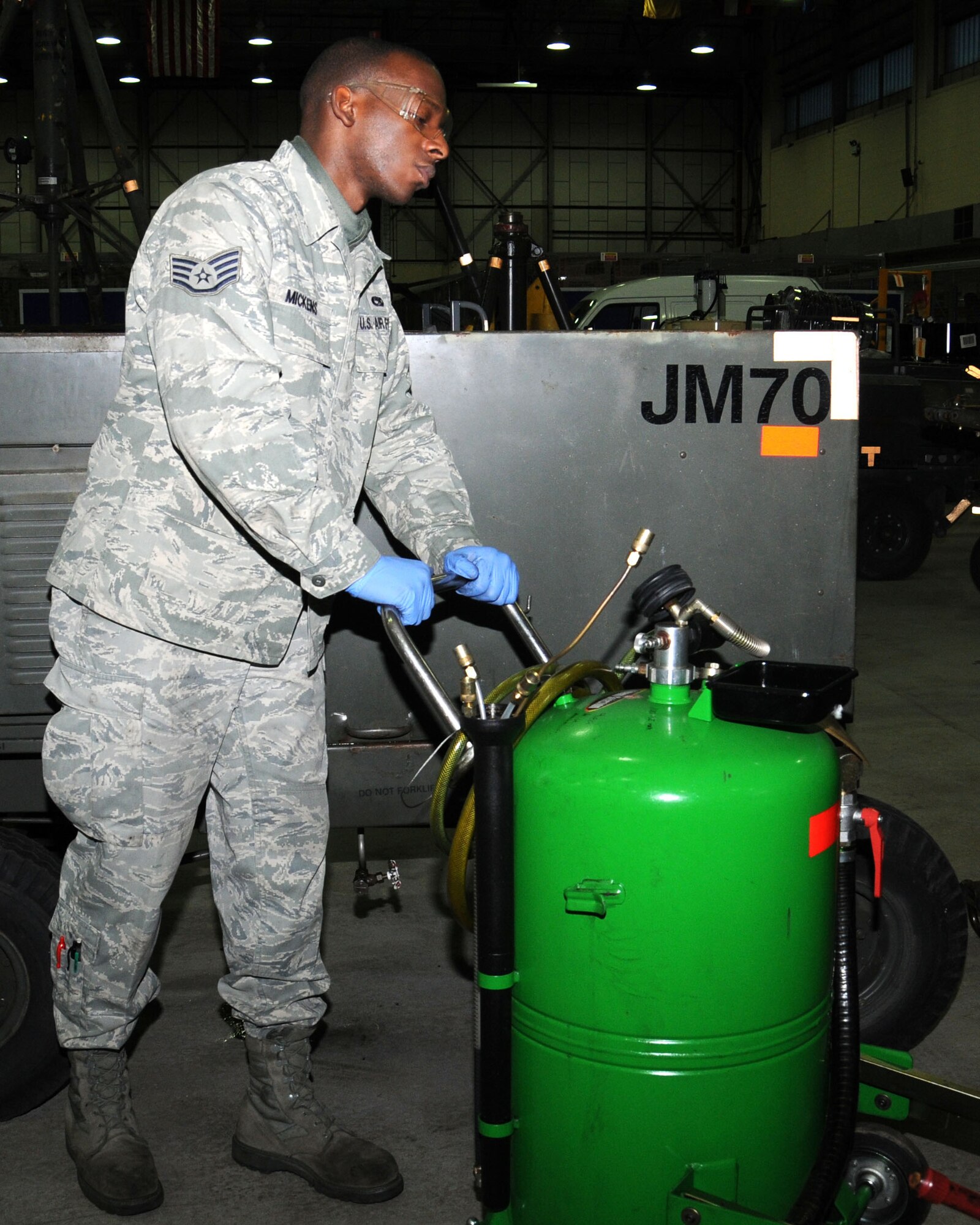 Staff Sgt. Reginald Mickens, 100th Maintenance Squadron Aerospace Ground Equipment journeyman from Sumter, S.C., moves an extraction tray used to catch used oil during a change of oil Jan. 30, 2013, at RAF Mildenhall, England. The section performs other inspections every six months on their assigned equipment to ensure they are mission-ready. (U.S. Air Force photo by Gina Randall/Released)