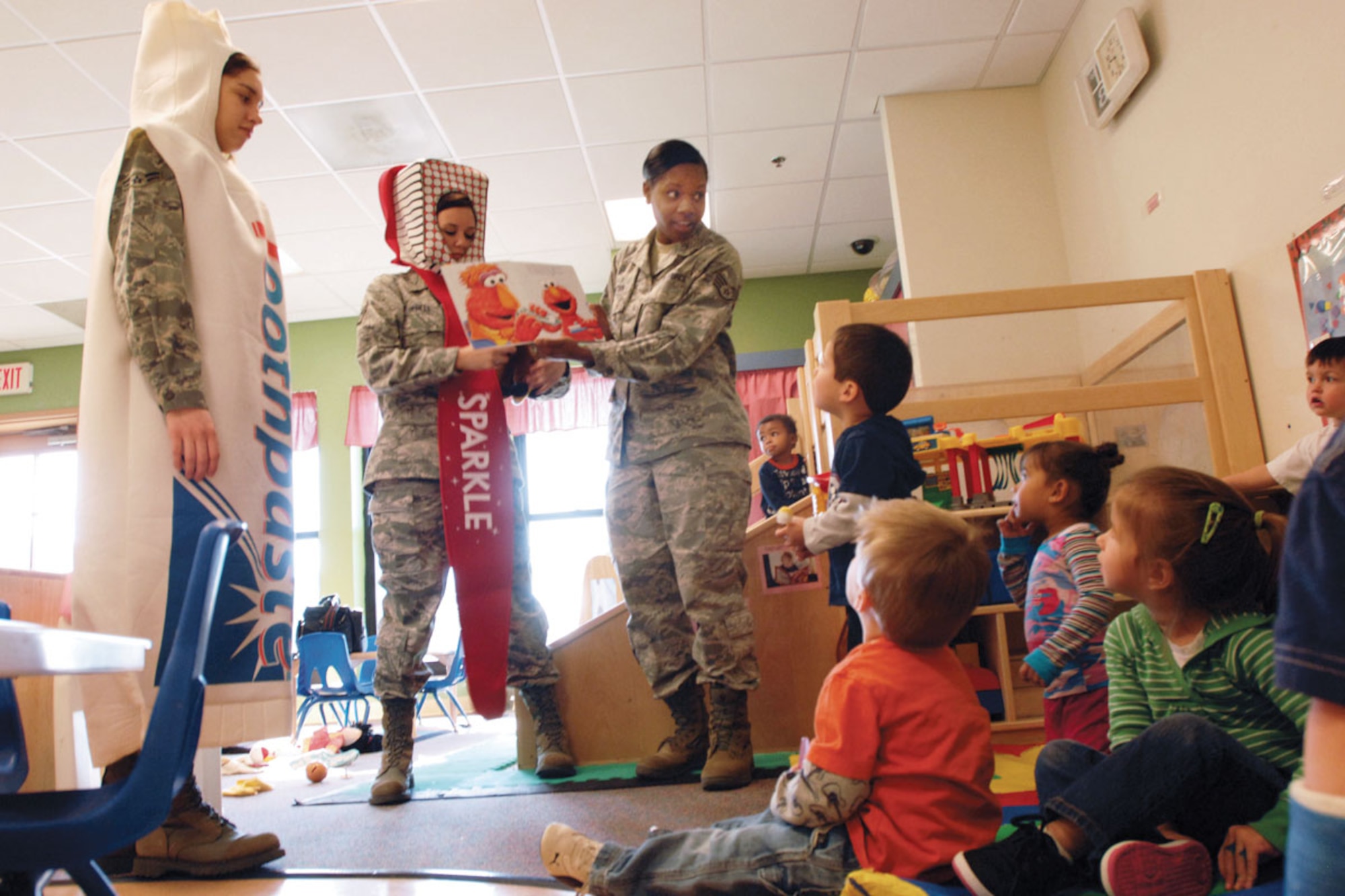 Airmen dressed as a toothbrush and tube of toothpaste teach children how to brush their teeth at a child development center as part of National Children’s Dental Health Month. (U.S. Air Force photo by Staff Sgt. Robert Barnett)