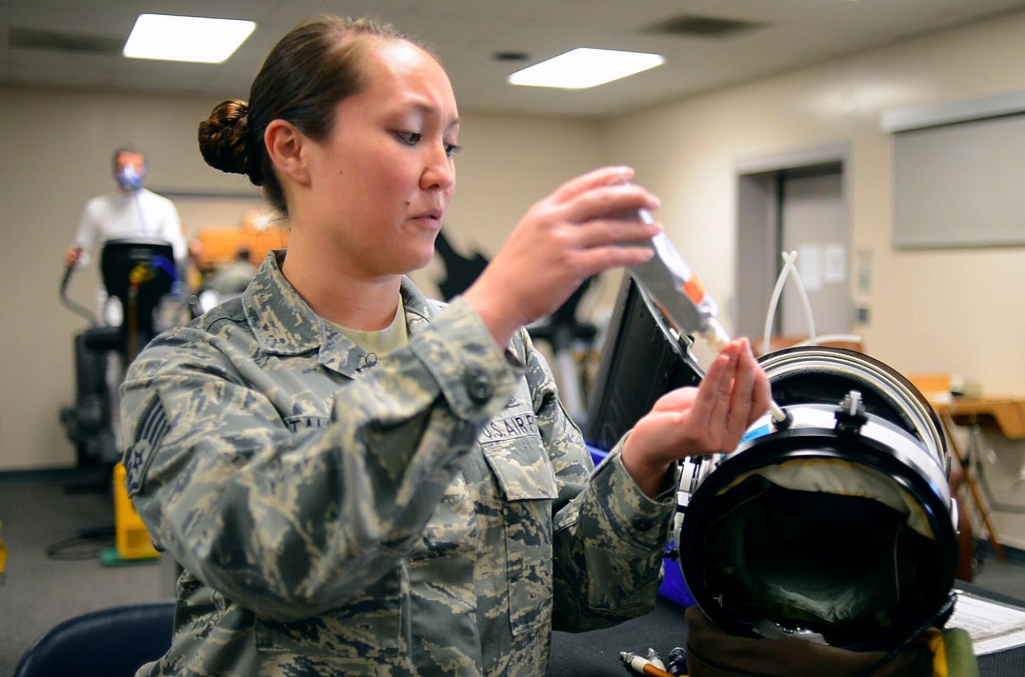 Staff Sgt. Suzzett Stalesky, 9th Physiological Support Squadron launch and recovery technician, demonstrates the use of tube food by inserting it into the feeding port of a U-2 full pressure suit helmet at Beale Air Force Base, Calif., Feb. 5, 2013. The U-2 is the only aircraft in the Department of Defense inventory that requires the utilization of a full pressure suit. (U.S. Air Force photo by Airman 1st Class Drew Buchanan/Released)