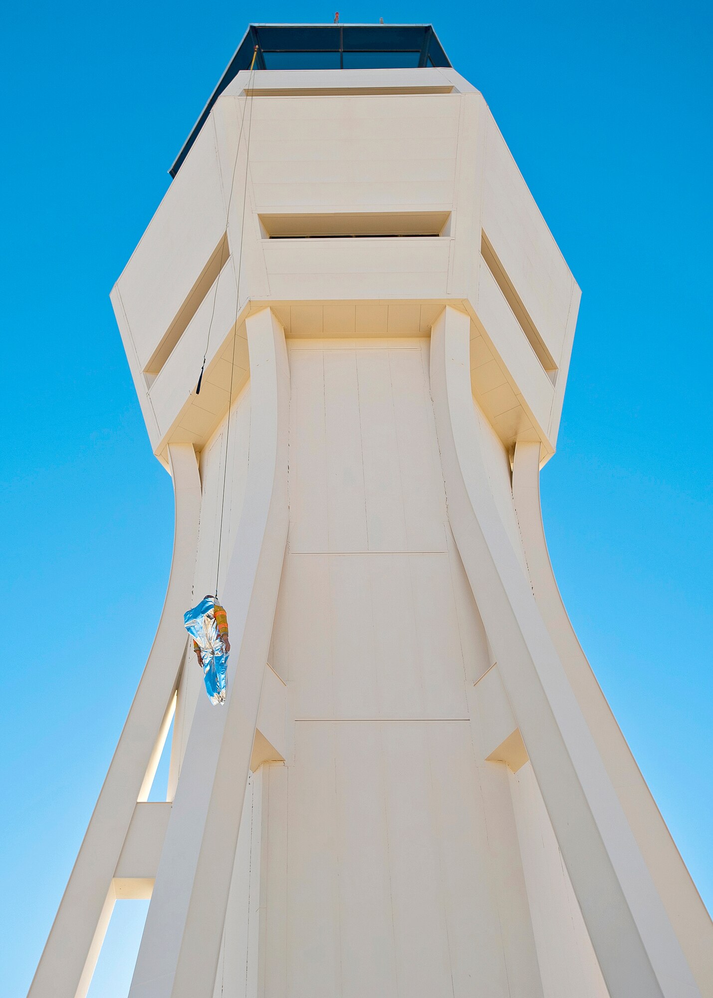 Personnel from the Edwards Air Traffic Control tower, along with the Edwards Fire Department and representatives from High Rise Escape Systems, Inc., test out the tower's latest acquisition of a controlled descent device with a mannequin. The HRES is a controlled descent device that is attached to a swing-arm bracket that is capable of lowering individuals safely to the ground, via a harness or oversized evacuation pant suit. (U.S. Air Force photo by Ethan Wagner)