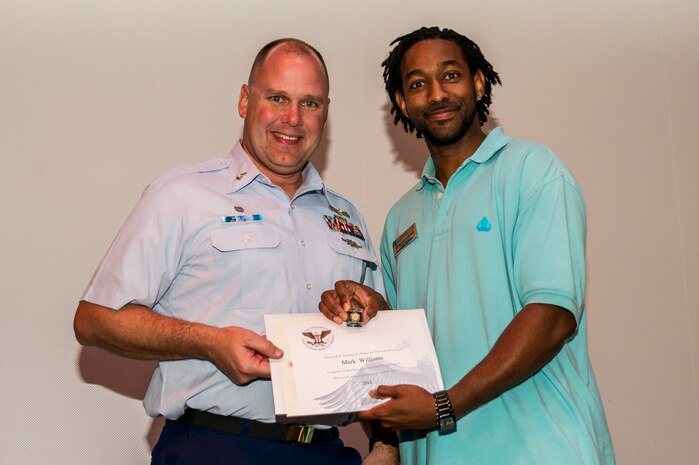 Mark Williams accepts an award from Lamar Moorehead, Youth Programs teen coordinator, during the Youth Programs Volunteer Recognition Ceremony Jan. 30, 2013, at Joint Base Charleston - Weapons Station, S.C. Williams volunteered 80 hours as a Youth Sports Baseball coach and referee, 160 hours as a Youth Sports Flag Football coach, and 160 hours as a Youth Sports Soccer coach. More than 15 members from Team Charleston's community were honored during the ceremony. (U.S. Air Force photo/ Senior Airman George Goslin)