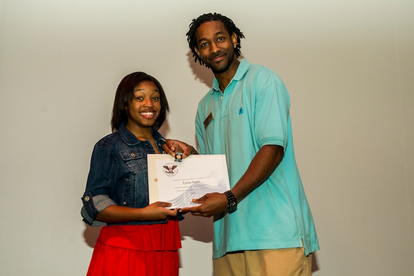 Tyrene Fields accepts an award from Lamar Moorehead, Youth Programs teen coordinator, during the Youth Programs Volunteer Recognition Ceremony Jan. 30, 2013, at Joint Base Charleston - Weapons Station, S.C. Fields volunteered 220 hours as a Junior Staff Volunteer with the School Age Sumer Camp Program and volunteered 100 hours as a Cheerleading Coach for the Youth Sports Flag Football team. More than 15 members from Team Charleston's community were honored during the ceremony. (U.S. Air Force photo/ Senior Airman George Goslin)