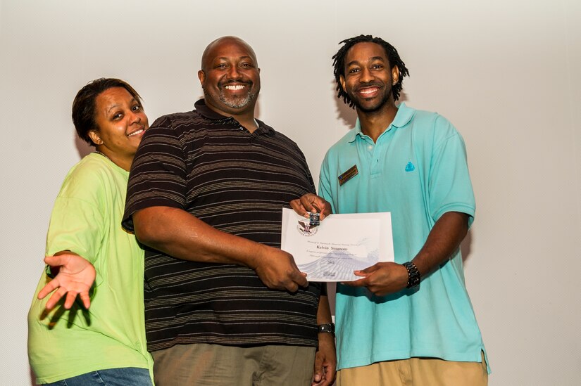 Kelvin Simmons accepts an award from Lamar Moorehead, Youth Programs teen coordinator, during the Youth Programs Volunteer Recognition Ceremony Jan. 30, 2013, at Joint Base Charleston - Weapons Station, S.C. Simmons volunteered 80 hours as a Youth Sports Baseball coach and 80 hours as a Youth Sports Soccer coach. More than 15 members from Team Charleston's community were honored during the ceremony. (U.S. Air Force photo/ Senior Airman George Goslin)