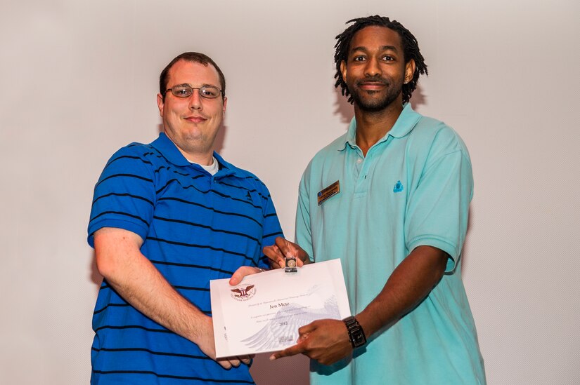 Jon Metz accepts an award from Lamar Moorehead, Youth Programs teen coordinator, during the Youth Programs Volunteer Recognition Ceremony Jan. 30, 2013, at Joint Base Charleston - Weapons Station, S.C. Metz volunteered as a Youth Sports Basketball coach and 80 hours as a Youth Sports Soccer coach. More than 15 members from Team Charleston's community were honored during the ceremony. (U.S. Air Force photo/ Senior Airman George Goslin)