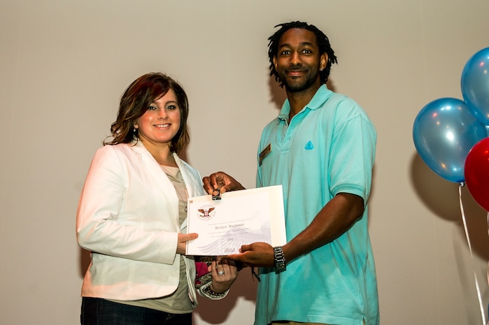Kristyn Buchanan accepts an award from Lamar Moorehead, Youth Programs teen coordinator, during the Youth Programs Volunteer Recognition Ceremony Jan. 30, 2013, at Joint Base Charleston - Weapons Station, S.C. Buchanan volunteered 80 hours as a Youth Sports Cheerleader coach. More than 15 members from Team Charleston's community were honored during the ceremony. (U.S. Air Force photo/ Senior Airman George Goslin)