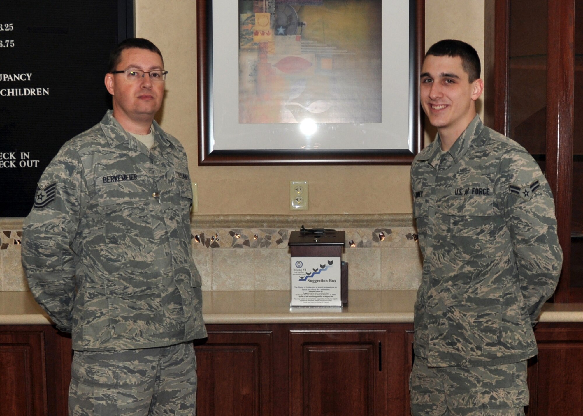 NIAGARA FALLS AIR RESERVE STATION, N.Y. - Tech. Sgt. Scott Berkemeier, 914th Communications Squadron, and Airman 1st Class Jordan Kinney, 328th Airlift Squadron, set up the Rising VI suggestion box in the base secondary lodging facility here February 2, 2013. The Rising VI is a base organization that strives to promote professionalism throughout the enlisted ranks. The suggestion box allows members to have a say in matters pertaining to their career in the Air Force. (U.S. Air Force photo by Staff Sgt. Stephanie Clark)