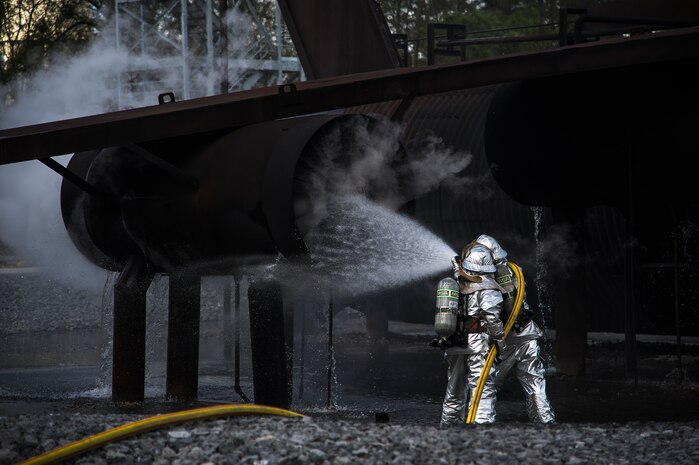Michael Ruey and Senior Airman Justin Fleishmann, 628th Civil Engineer Squadron firefighters, pour water on a training aircraft Jan. 30, 2013, at Joint Base Charleston - Air Base, S.C. The static training aircraft allows 628th CES firefighters the opportunity to practice their fire response abilities in case of an actual emergency. (U.S. Air Force photo/Staff Sgt. Rasheen Douglas)