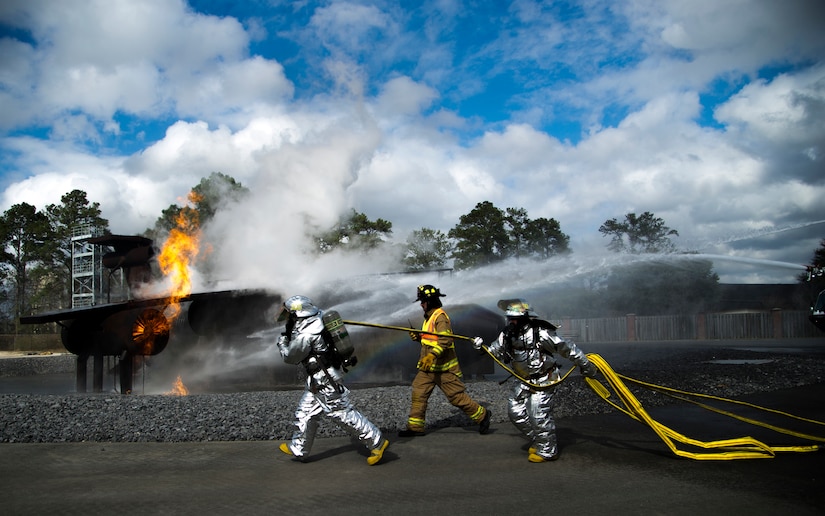 Senior Airman Justin Fleishmann and Michael Ruey rush hoses to the static training aircraft to extinguish the fire as Lead Firefighter Mark Johnson evaluates their performance Jan. 30, 2013, at Joint Base Charleston - Air Base, S.C. Fleishmann, Ruey, and Johnson are 628th Civil Engineer Squadron firefighters. The static training aircraft allows 628th CES firefighters the opportunity to practice their fire response abilities in case of an actual emergency. (U.S. Air Force photo/Staff Sgt. Rasheen Douglas)