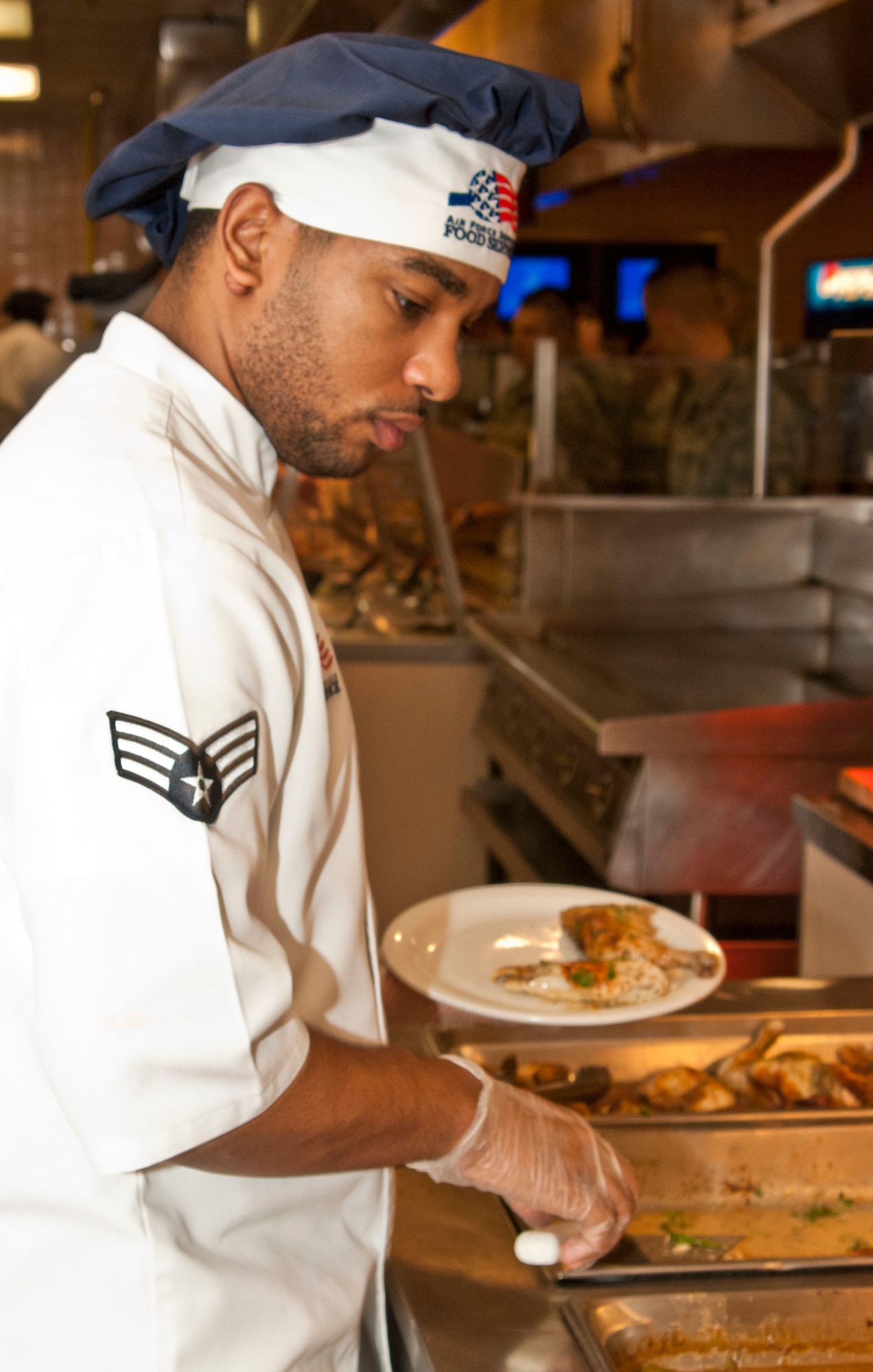 Senior Airman Anthony Crider, 99th Force Support Squadron services journeyman, prepares a plate of food for customers during lunch time at the Crosswinds Inn dining facility Feb. 5. The dining facilities offer Airmen a wide variety of food choices to enhance their dining experience.  (U.S. Air Force photo by Airman 1st Class Monet Villacorte)