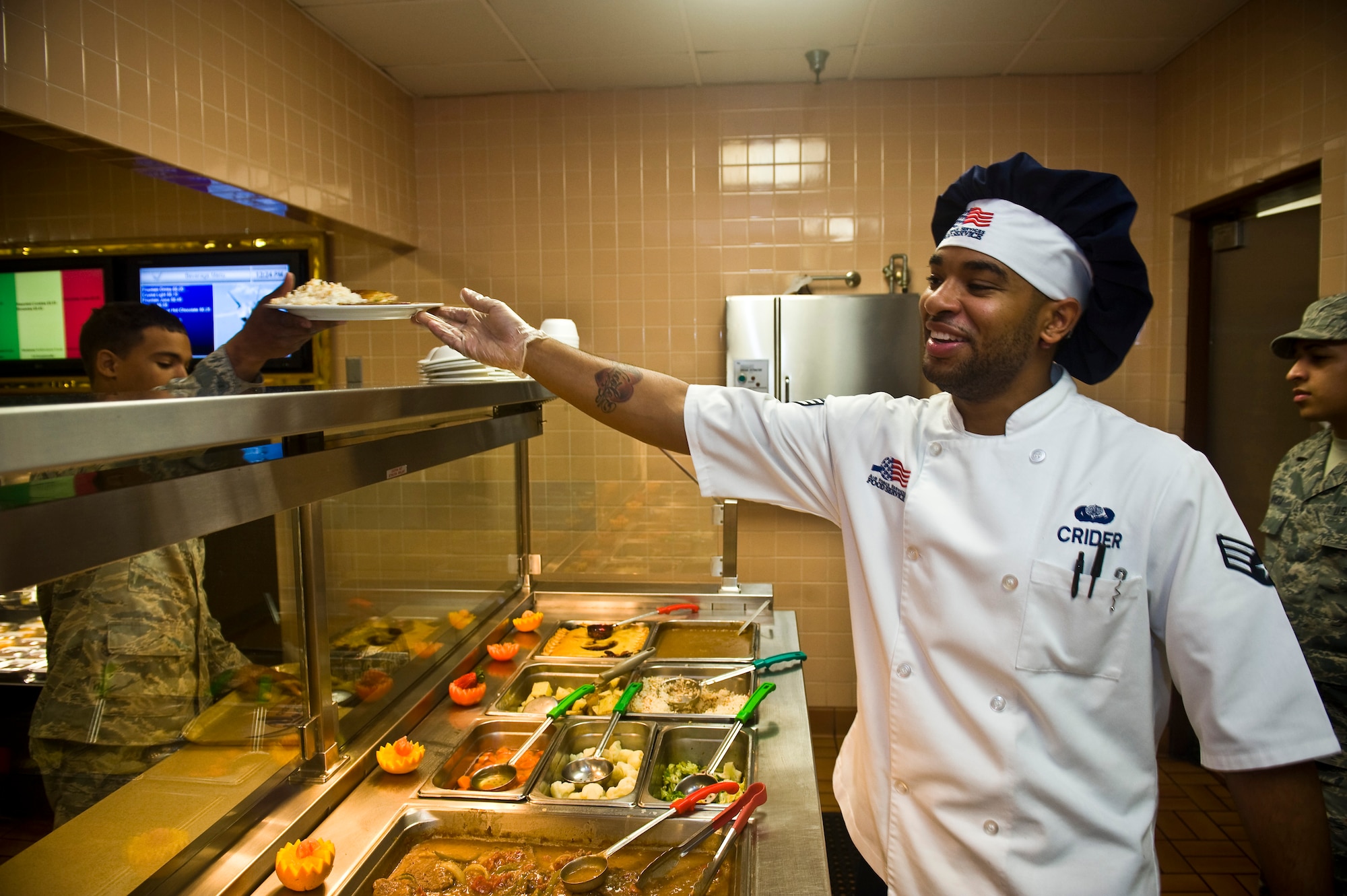 U.S. Air Force Senior Airman Anthony Crider, 99th Force Support Squadron services journeyman, hands a plate of food to an Airman at the Crosswinds Dining Facility, Feb. 5, 2013, on Nellis Air Force Base, Nev. The Crosswinds at Nellis is competing to receive the Hennessy Award which is presented to Air Force installations having the best food service program in the Air Force (U.S. Air Force photo/Senior Airman Brett Clashman)
