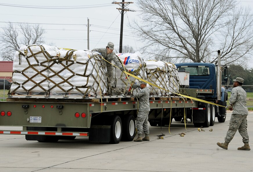 Senior Airmen Katie Gordert, Pierre Brown and Marcus Hayes, 2nd Logistics Readiness Squadron Vehicle Operations, prep aircraft pallets on a flatbed truck for transport on Barksdale Air Force Base, La., Feb. 5. More than 42,000 pounds of rice was palletized by Airmen from the 2 LRS air terminal operations for transport from the base to Port au Prince, Haiti, in support of Children's Lifeline Foundation. (U.S. Air Force photo/Staff Sgt. Amber Ashcraft)