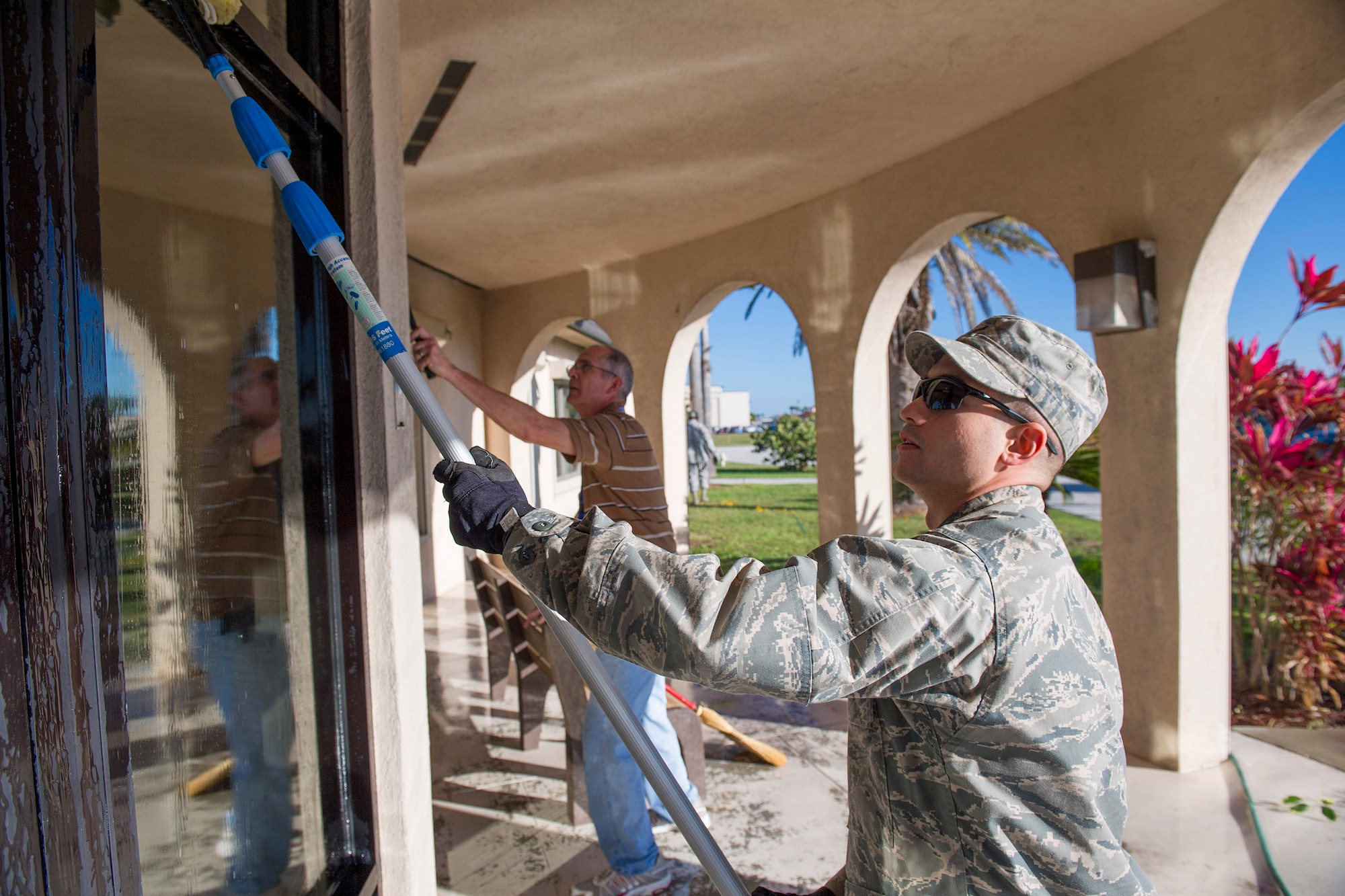 Lt. Jonathan Paz, 45th Civil Engineer Squadron, gives the windows at the
Housing Office a thorough cleaning during "Pride Day" held Feb. 1 held all
around Patrick Air Force Base and Cape Canaveral Air Force Station. In the
background is Ed Bayba, 45th Space Wing Housing Manager. (U.S. Air Force Photo/Matthew Jurgens)
