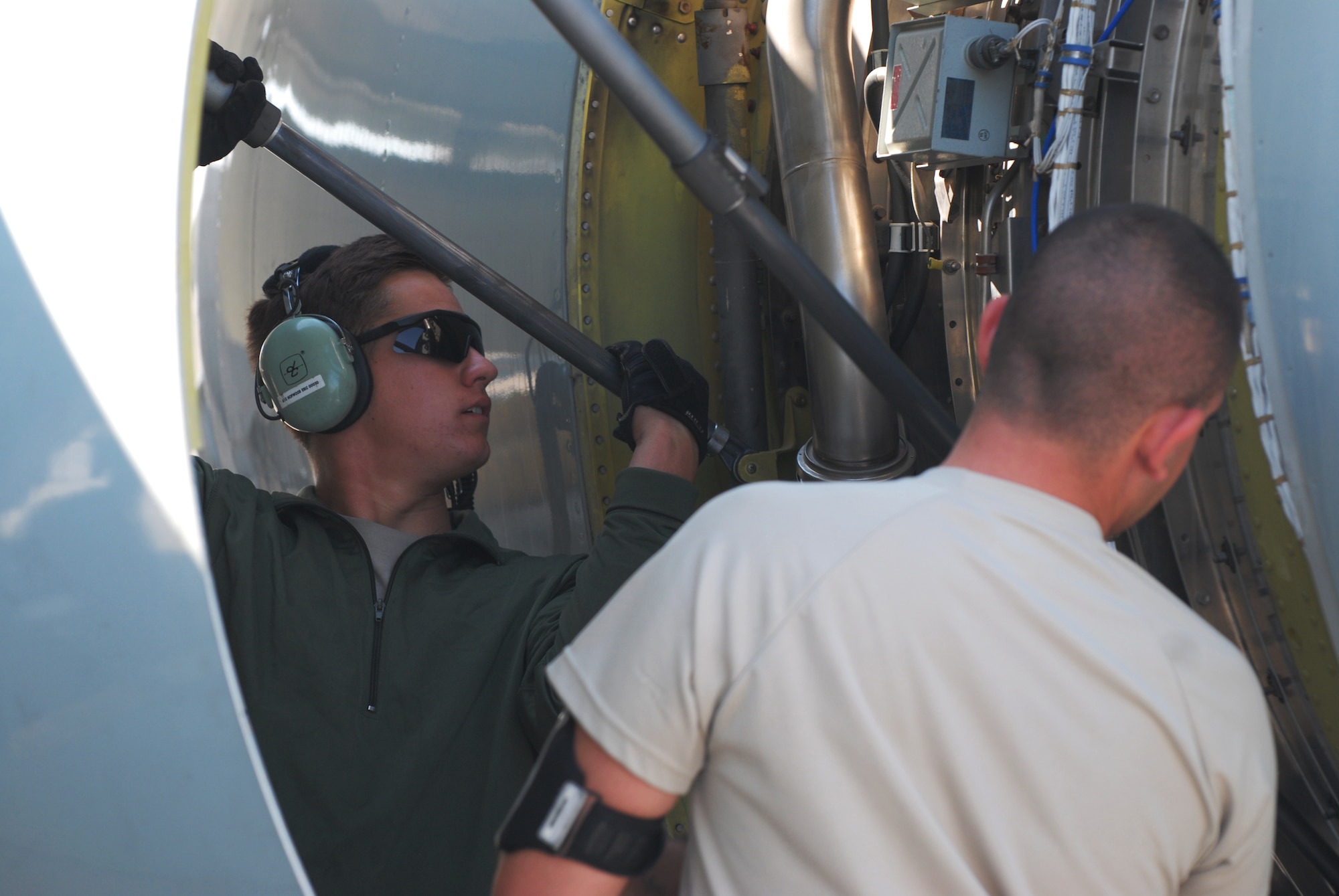 SOUTHWEST ASIA -- Airman 1st Class Eric Hopwood and Senior Airman Garier Grau open a cowling panel on the jet engine of a RC-135 Rivet Joint, Feb. 2. Deployed from Offutt Air Force Base, Neb., members of the 55th Aircraft Maintenance Squadron serve as the 763rd Expeditionary Aircraft Maintenance Unit for the 379th Air Expeditionary Wing in Southwest Asia. The Rivet Joint program they support generates airpower for real-time collection, analysis and dissemination of signal intelligence to provide air dominance over the area of operations. (U.S. Air Force photo/Master Sgt. Christian Michael)