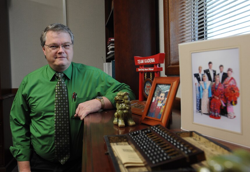 Mark Pinnau, 718th Civil Engineer Squadron deputy commander, kneels next to his awards and family photos in his office on Kadena Air Base, Japan, Feb. 6, 2013. Pinnau won the Harry P. Rietman Award at the Pacific Air Force and Air Force levels for his hard work and dedication. (U.S. Air Force photo/Airman 1st Class Malia Jenkins)